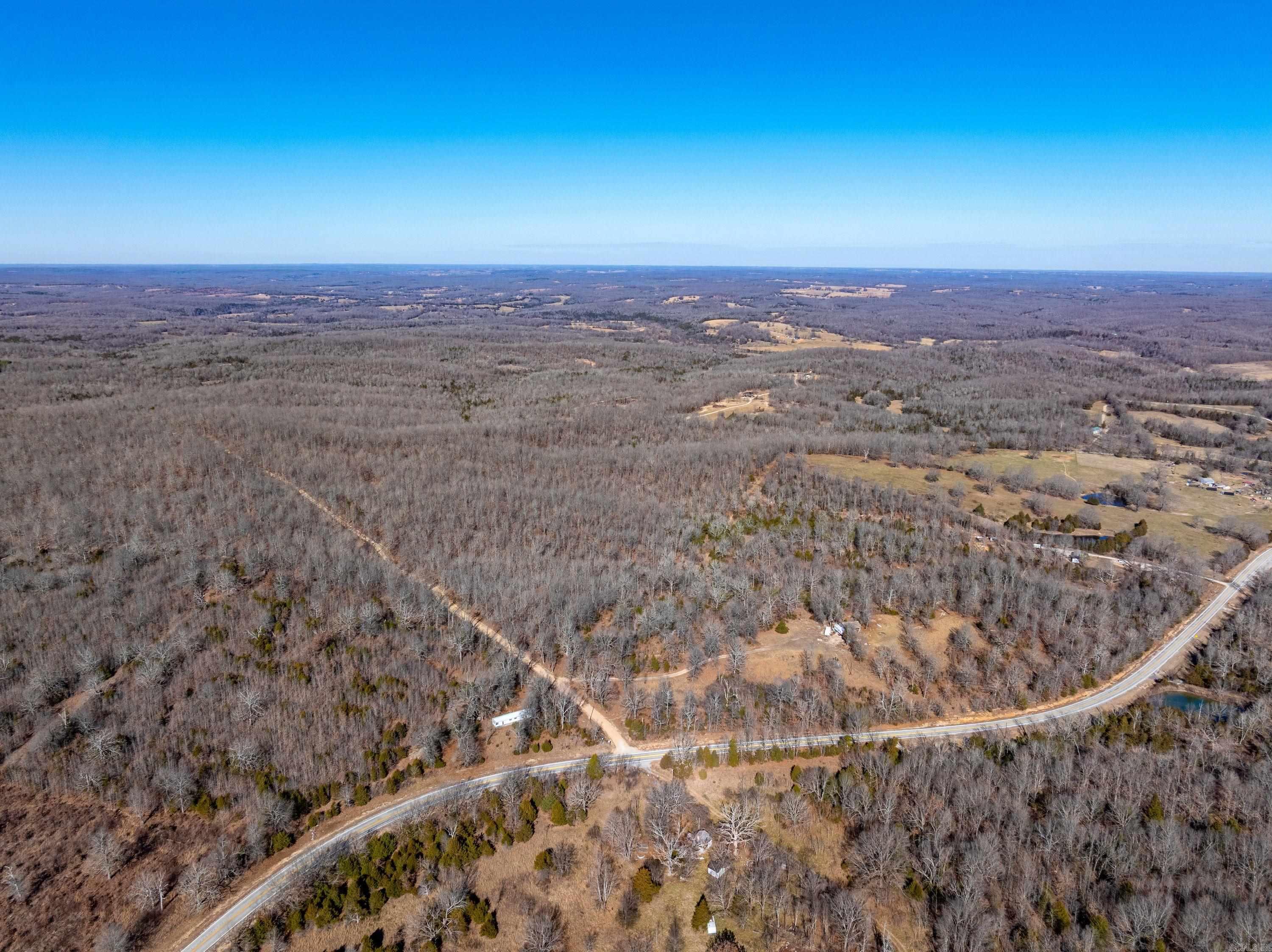 Rare opportunity to own approximately 345 +/- contiguous acres located just north of the community of Saddle, near Mammoth Spring, Arkansas, in Fulton County. Large acreage tracts like this seldom come available in this area. The only separation between parcels is Quail Creek Road, making the land highly usable and easily accessible. The front parcel lies along Highway 289 and offers county water and electric. An older cabin is located here and is currently dilapidated but could potentially be restored with significant work. A small pasture area is present and could be improved if desired. As you travel down Quail Creek Road, the remaining 320 +/- acres open into a well-managed hunting and recreational tract featuring beautiful mature timber, gently rolling terrain, and an excellent system of trails throughout the property. The land is not steep and is easy to navigate by ATV or vehicle. This property is set up for hunting with strategically placed food plots, deer stands, and excellent habitat for whitetail deer and turkey. Some fencing is in place, though the entire perimeter is not fenced. Access is provided by gravel roads, allowing for year-round entry.