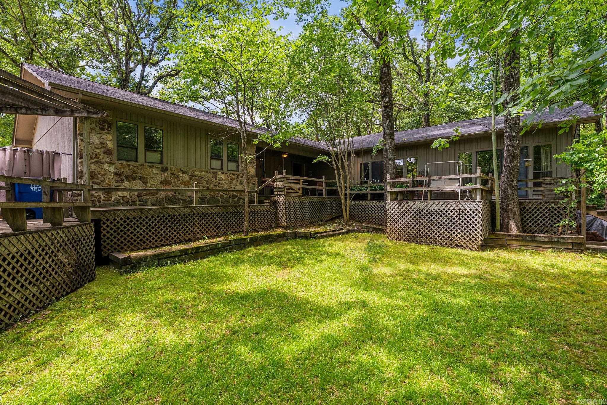 Find Yourself on Flintrock. Tucked behind a wall of greenery in the wonderful Indian Hills neighborhood of North Little Rock, your front yard offers a sense of seclusion that's rare to find — and even harder to leave. Step inside and you're greeted by a warm, inviting living room with engineered hardwood floors that carry you through the home. To the left, the kitchen and dining space flow naturally together. Down the hall, three bedrooms — one en-suite, two sharing a guest bath — all with the kind of generous room sizes that remind you homes used to be built with comfort in mind. Then there's the primary suite. An addition made by previous owners with intention and care. A 4th bedroom, a large bath suite, and a sitting room currently used as an art studio — light pouring through oversized windows, a sliding door opening to your deck and the wooded privacy beyond. Out back, a deck patio leads to something you simply don't find every day — a full-sized tennis court. Refinish it for tennis, convert it to pickleball, or use it as a fully fenced play space for kids and friends. The possibilities are endless. Truly a one of a kind home and its ready for its next owner.