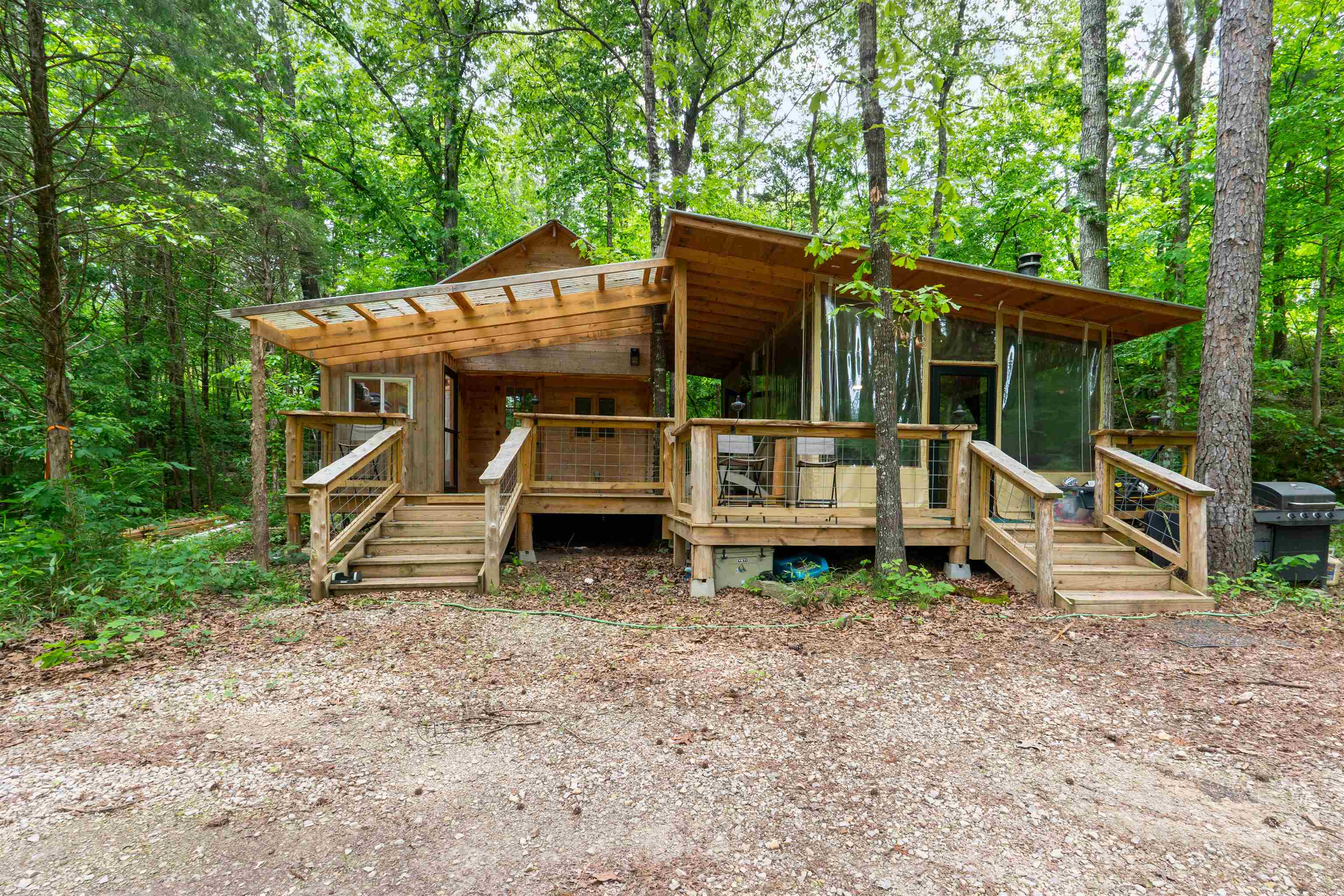 Escape to your own private retreat on beautiful Piney Creek! Tucked away on 3 secluded acres, this unique cabin offers the perfect blend of rustic charm and outdoor living. Featuring 1 bedroom, a loft area, 1 bathroom, and a versatile kitchen/living space that can be fully enclosed or opened up to enjoy the fresh air and peaceful surroundings. Cozy up by the wood burning stove or relax on the spacious porch areas. A walkway leads you down to the creek, creating the perfect spot to unwind and enjoy nature. The property also includes 2 storage buildings, one of which is fully insulated for added functionality. Whether you’re looking for a weekend getaway, full-time retreat, or an incredible Airbnb opportunity, this one of a kind creekside cabin is a must see!