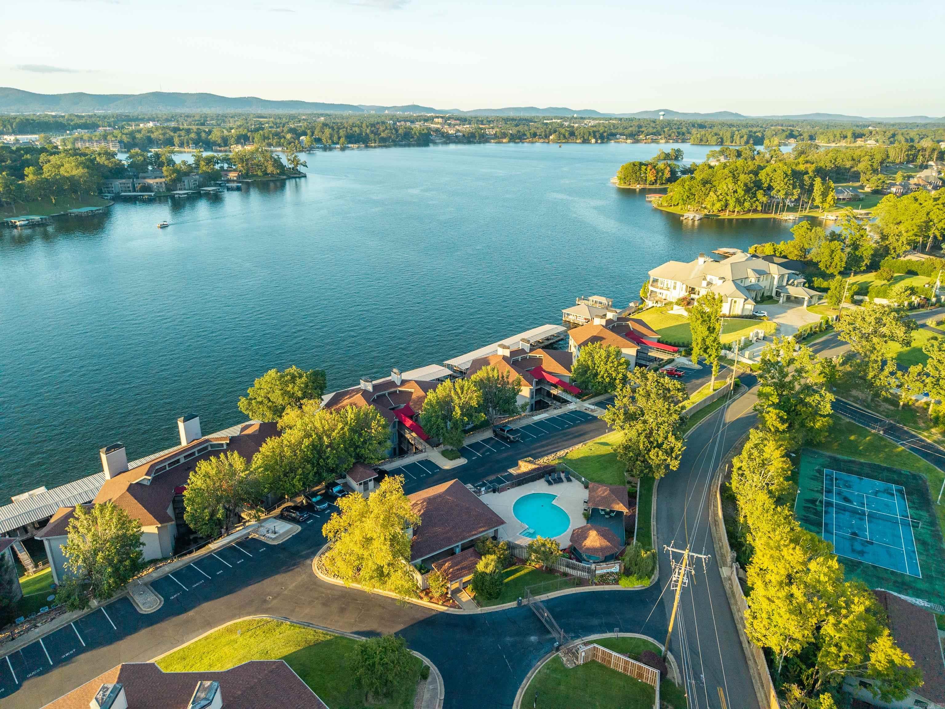 Let the stay and play begin! This condominium is a one of a kind with big views, comfort and convenience. Stoneridge is a gated community located just off Hwy 7S or Central Avenue on beautiful Lake Hamilton with great access to dining, shopping, Oaklawn Hot Springs Racing and Casino. The interior design is upped with chiseled granite countertops in the kitchen, brick accents that set off the bar and dining area, quartz countertops in the bathrooms, and snazzy tiled showers. Lots of natural light fills the space through oversized windows and sliding doors so you can drink in the landscape. Settle in during the cooler months with the alluring LED fireplace and views of beautiful fall foliage. Yes, there is a covered boat slip and a reserved parking space with this incredible property. This prime condominium is currently a short-term rental with an active calendar so be sure to make an appointment in advance to find an opening to see this remarkable property.
