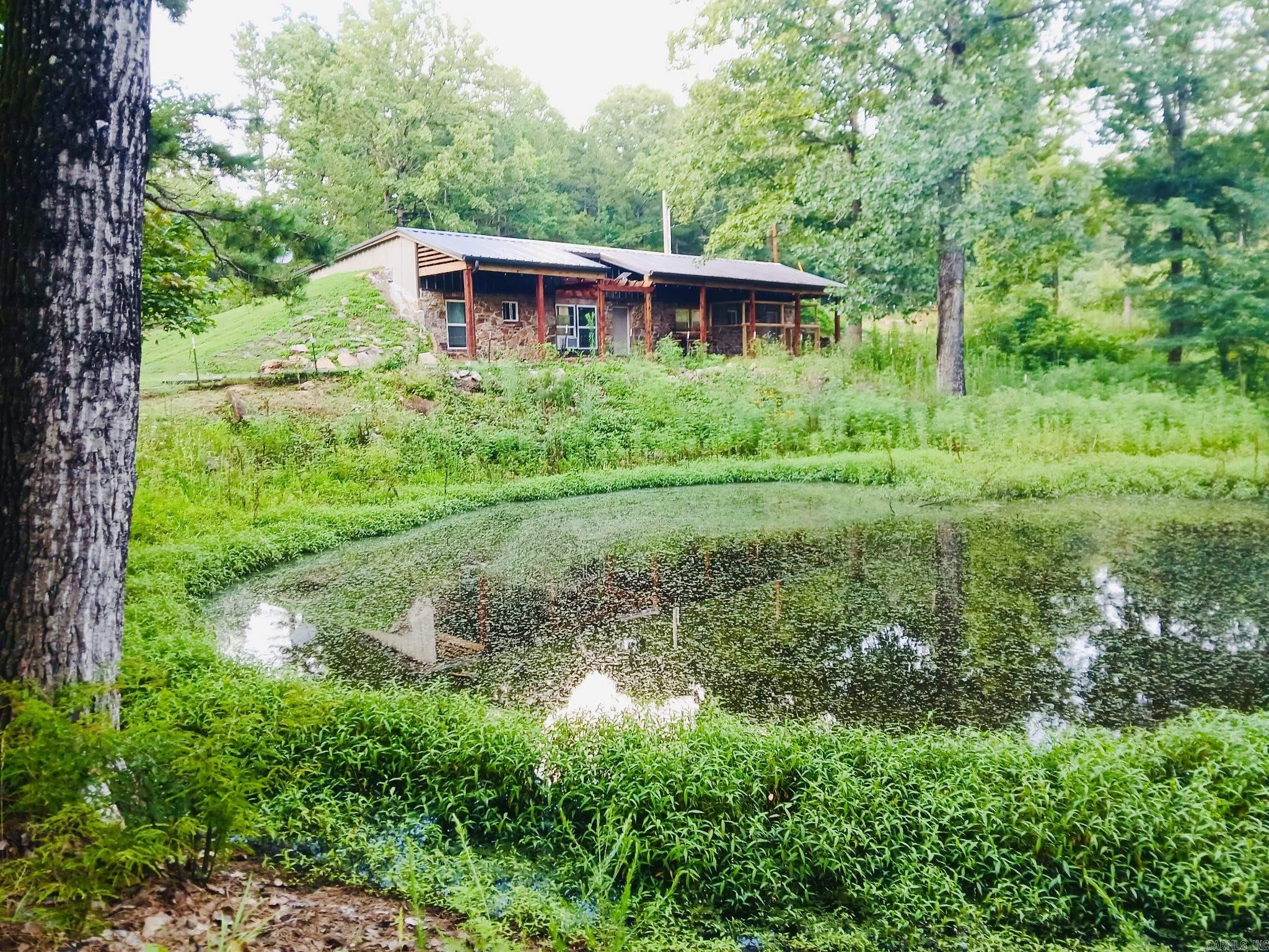 Unique find! This earth-sheltered home with walk-out front is a unique find in a beautiful setting! The partially underground home is designed to provide exceptional energy efficiency, structural resilience, protection against severe weather, and low exterior maintenance. The 12.29 acres MOL includes fencing, a pond, pasture, and mature shade trees ideal for a hobby farm, raising livestock, and gardening. Enjoy morning coffee or quiet evenings sitting on the covered front porch enjoying the views overlooking the pond or watching deer, birds, and small game. The spacious 2 bedroom, 1 1/2 bath home offers over 1300 sq feet with several recent updates including new metal roofing, guttering, windows, cedar accents, hot water heater, plus new fencing, fire pit area, and new door for the detached garage. Some furniture and furnishings may also be available to convey with the sale. Whether you're seeking a forever or vacation home or a nightly rental this unique property checks so many boxes, plus it is privately located yet only a few minutes from downtown Melbourne, White River for world-class Trout fishing, and Cooper's Hawk, an 18-hole championship golf course! Nice property!