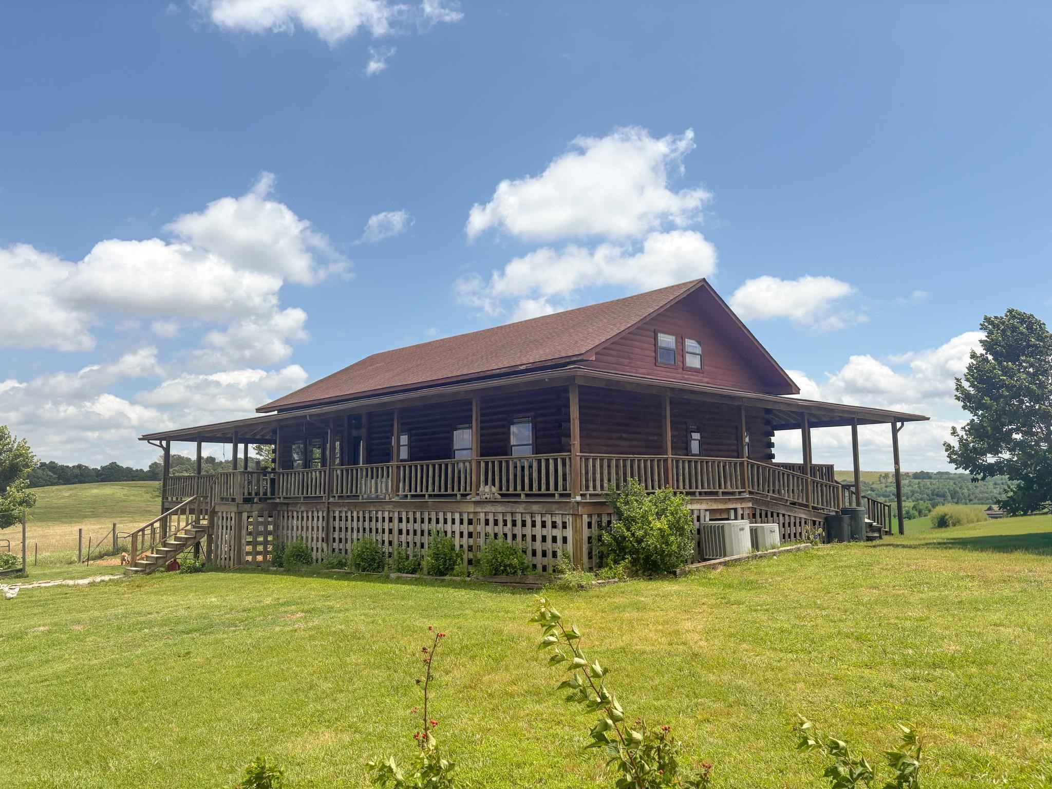 Stunning 2,500 SF log home on 67.4± acres in Stone County with breathtaking panoramic Ozarks views! This 4BD/2BA property sits high on the hilltop with a full wrap-around porch perfect for taking in the scenery. Fenced pasture, wooded hunting land, spring-fed pond, fruit trees, berry bushes & established raised garden beds make this a true homesteader's dream. The 2,700± SF shop with its own electric panel is ideal for equipment, livestock, or a workshop operation. Full walkout basement adds additional space and functionality. Well (400 ft), septic & 1,000-gal propane. Interior has been thoughtfully updated throughout — come see it for yourself. 67.4 acres of Ozarks opportunity minutes from Mountain View. Properties like this don't come around often. Call today!