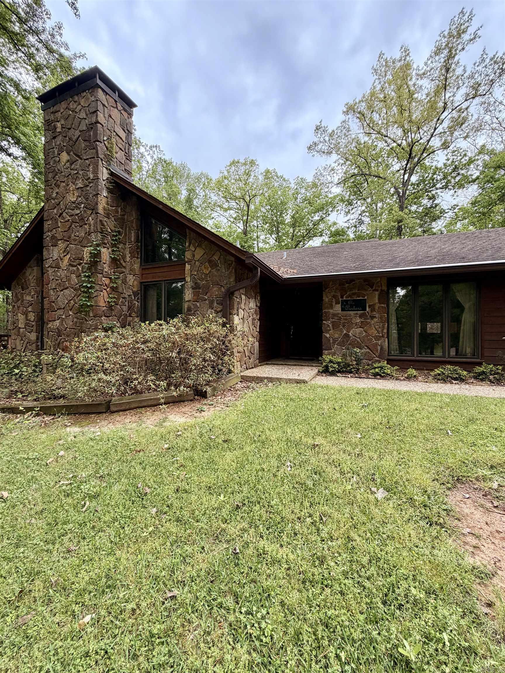 Perched on 2.62 acres in a beautiful hilltop setting, this stunning 4BR/2.5BA stone and cedar home offers space, character, and exceptional features throughout. The living room showcases a dramatic stone fireplace, vaulted wood ceilings, wet bar, and built-in entertainment center, along with Pella windows featuring built-in blinds. The adjoining kitchen and dining area boast rich Wood-Mode cabinetry, center island with Jenn-Air cooktop, appliance garage, trash compactor, pantry, double ovens, and a skylight you can open or close as desired. A spacious sewing room—complete with sink and built-in desk—would make a perfect craft, hobby, or exercise room. Just off the kitchen, the cozy family room features tongue-and-groove wood walls and opens to a large patio ideal for entertaining. The primary suite offers double sinks and a steam shower with timer. Three additional bedrooms are freshly painted with generous closets. Oversized garage, circular drive, whole-house generator, attic fan, and more. Square footage, lot size, and acreage is taken from courthouse records.