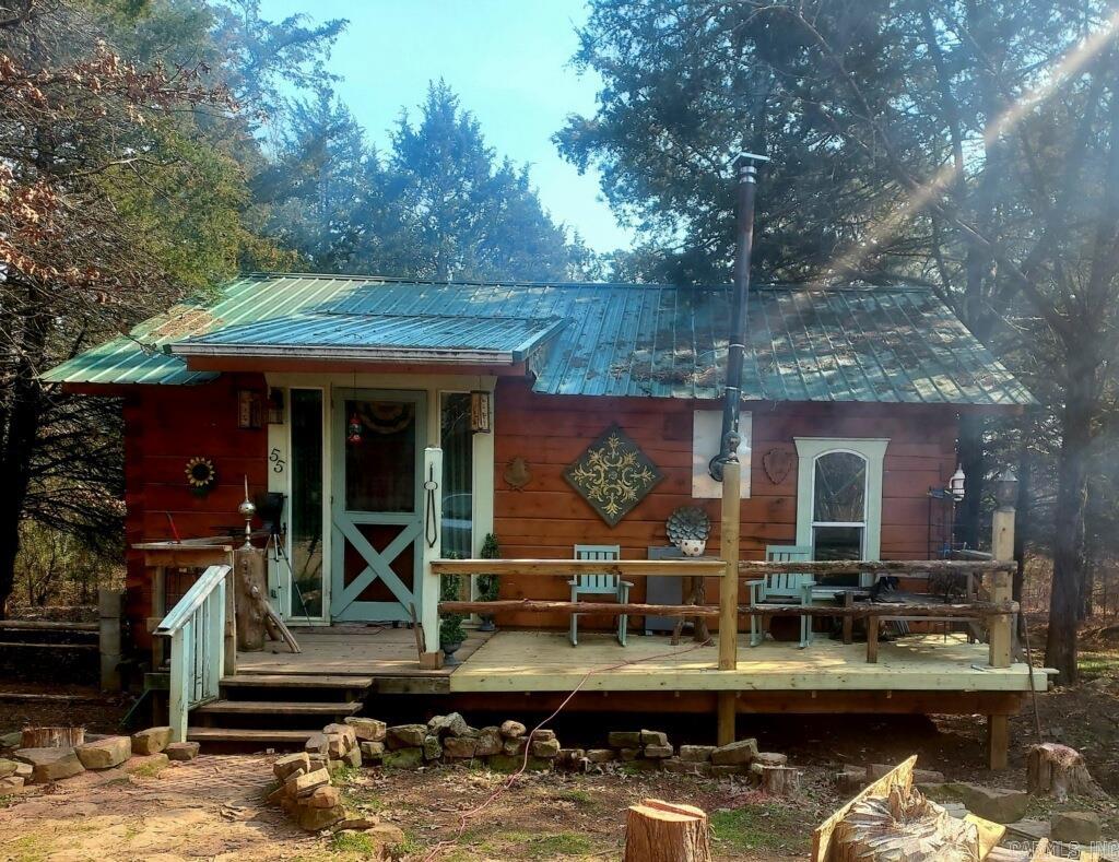 This property is a homesteader’s dream, incredible investment opportunity, or the perfect place to enjoy peaceful country living with room to grow. Situated on five beautiful acres near Wolley Hollow State Park and just minutes from Persimmon Ridge Disc Golf Course, this unique property offers privacy, recreation, and endless possibilities. The main cabin features approximately 784 sq ft with a one-bedroom studio layout, full kitchen, spacious living area, full bathroom, Samsung washer and dryer, and loft space for storage or additional sleeping. A large barn includes an additional apartment with one bedroom, full kitchen, full bath, and living area. Apartment square footage is unknown and not included in the listed square footage. Downstairs offers extra storage plus an additional room with electric and water already in place. The acreage includes cleared land ideal for gardening, livestock, or hobby farming, along with wooded ATV and walking trails. An additional metal barn with electric and water provides even more versatility. Don’t forget to pay your respects to “Old Boo,” the family dog who still watches over this amazing property.