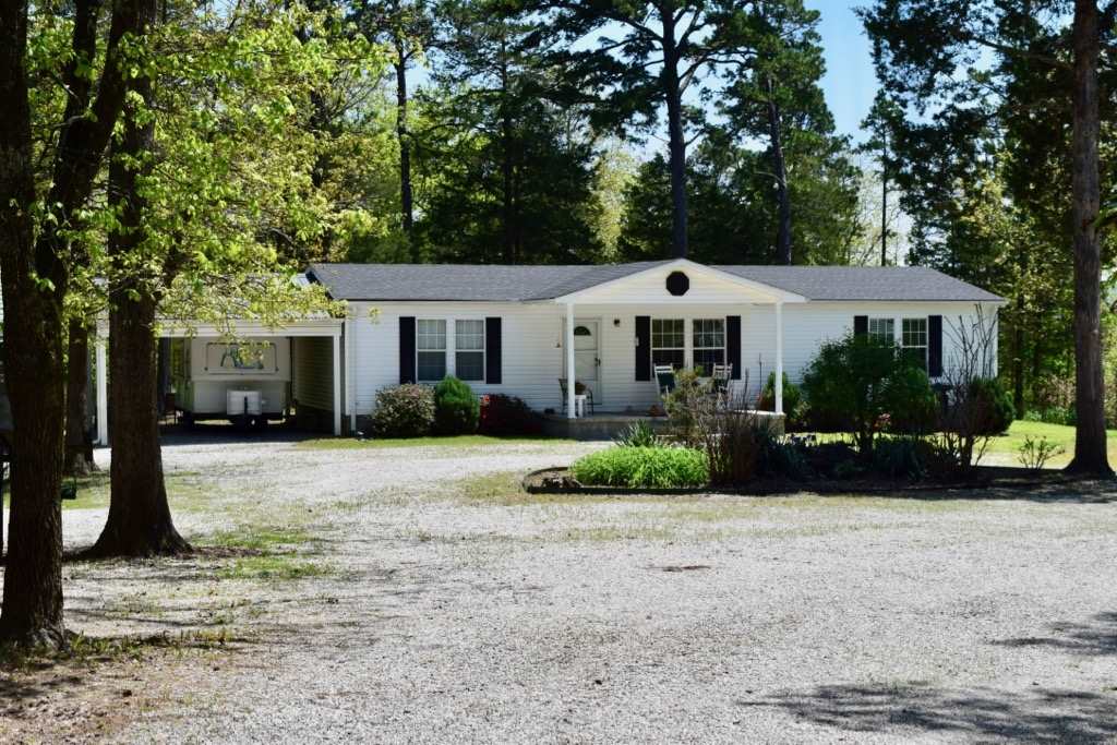 Well-maintained home on fabulous 5.3 manicured acre parcel.  Front porch, two 2-car carports, deck, outbuildings and shop with AC. Home has generator hookup and garden spot with rich soil. Underground electric, 2 RV hookups and circular drive. Close to town but in a beautiful private setting with wooded lane to Home. Property consists of 2 parcels, one a city lot with all the city services available and the home is built on county land with no restrictions. Great mountain views in fall and winter!