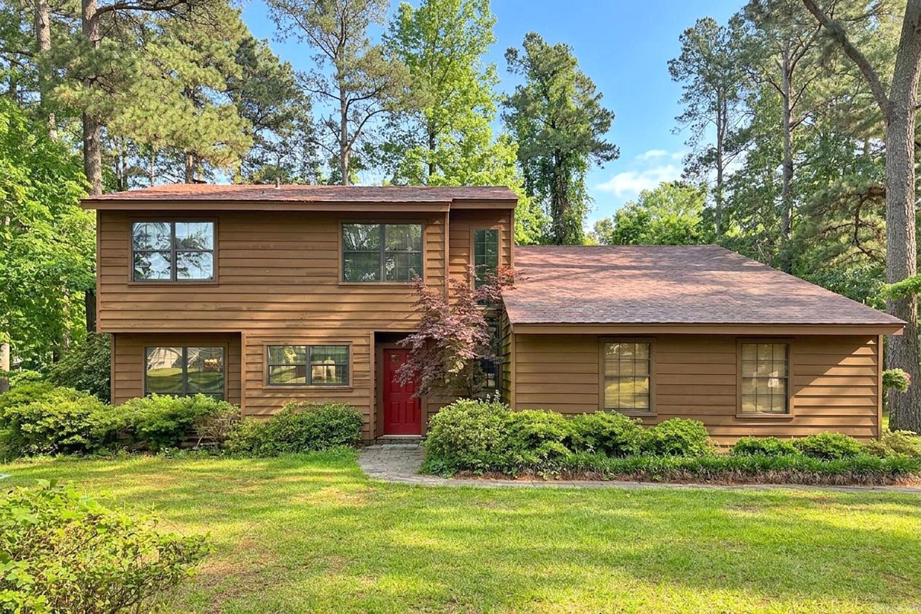 Rustic charm and lush surroundings meet on Caddo Circle! This two-story 1970s-style haven is surrounded by rolling green acreage and blooming bushes, complete with a small creek on the back of the property. Inside, the tall, half-vaulted ceilings and large windows allow in natural lighting, while the fireplace is made of stacked stone that is showcased all the way to the ceiling. Built-in bookshelves, parquet flooring, and an elevated dining area add to the mid-century allure of this residence. The primary bedroom is on the main floor and features two closets, one of which is a walk-in with custom built-in drawers. Upstairs two bedrooms are joined by a Jack and Jill style full bath, while the third upstairs bedroom is split away from the other two. This bedroom has a built-in desk and bookshelf, and is flanked by two huge walk-in storage spaces. One of these storage spaces is cedar-lined, and both closets run the length of the room. Down the driveway is a matching workshop, complete with electricity, with French-style bay doors to allow larger items to be stored. To sweeten the sale, the refrigerator, washer, dryer, AND the Cub Cadet stay with the property for the new homeowner.