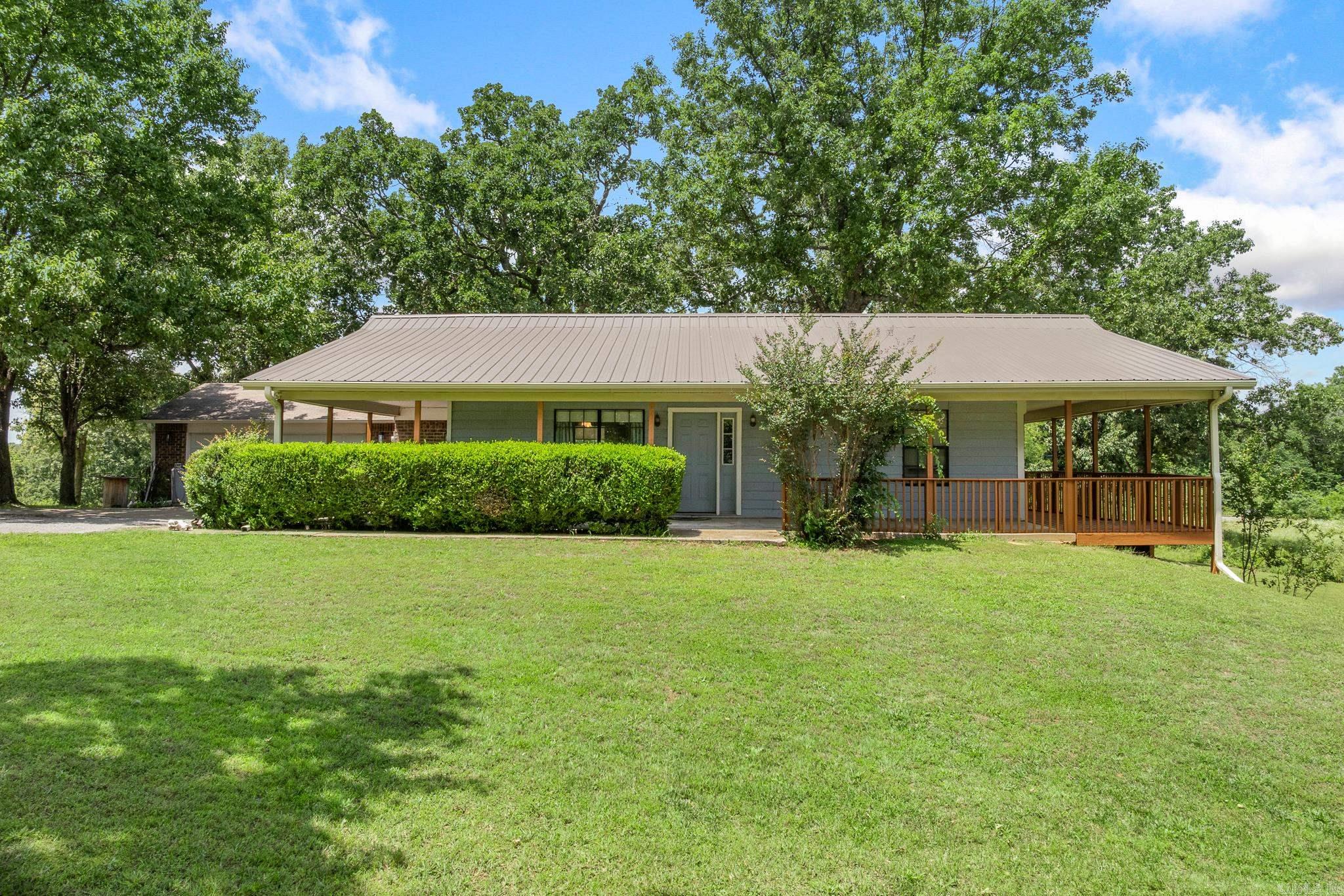 Beautiful home on 20.17 surveyed acres conveniently located between Harrison and Berryville, just off Hwy 62 E. This spacious 4-bed, 2-bath home offers 2,320 sq ft of living space with a finished walk-out basement and inviting wrap-around porch, perfect for enjoying the peaceful country setting. Recent updates include a new roof (2023), new water heater, new exterior HVAC unit, LPV flooring throughout, updated bathrooms, fresh deck stain, and energy-efficient LED lighting. The home is also wired for a whole-home generator for added peace of mind. An insulated, detached two-car garage is just steps from the home and is accessed through a spacious mudroom featuring a skylight, abundant storage, and room for a second refrigerator or freezer. The finished basement includes two beds, a second living area, wet bar, and built-in shelving, making it ideal for entertaining, guests, or multi-generational living. The 20.17 acres offers a beautiful blend of level pasture and mature trees, creating endless opportunities.