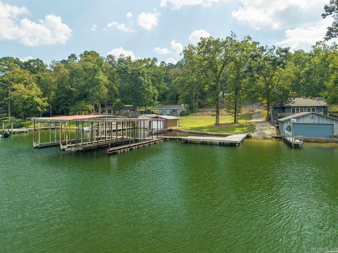 Beautiful Lake Hamilton lakefront lot ready for your dream home! This exceptional 0.58-acre property offers approximately 107 feet of shoreline, combining natural beauty with valuable improvements already in place for immediate enjoyment and future development. The property features a concrete seawall (permitted), private launching ramp, swim dock, and a two-stall covered boat dock. Each boat slip measures approximately 9’8” wide by 34’ long with 9’6” height clearance, providing ample space for most watercraft. A well-designed pier system includes an 8’ x 32’ walkway leading to a 12’ x 24’ swim platform—perfect for relaxing, entertaining, or enjoying the lake lifestyle. A standout feature of this lot is its favorable topography. Most of the property lies above the flood plain, offering a spacious and secure building site with a gentle slope to the water, making it ideal for a wide range of home designs. Utilities are already in place, adding significant value and convenience.