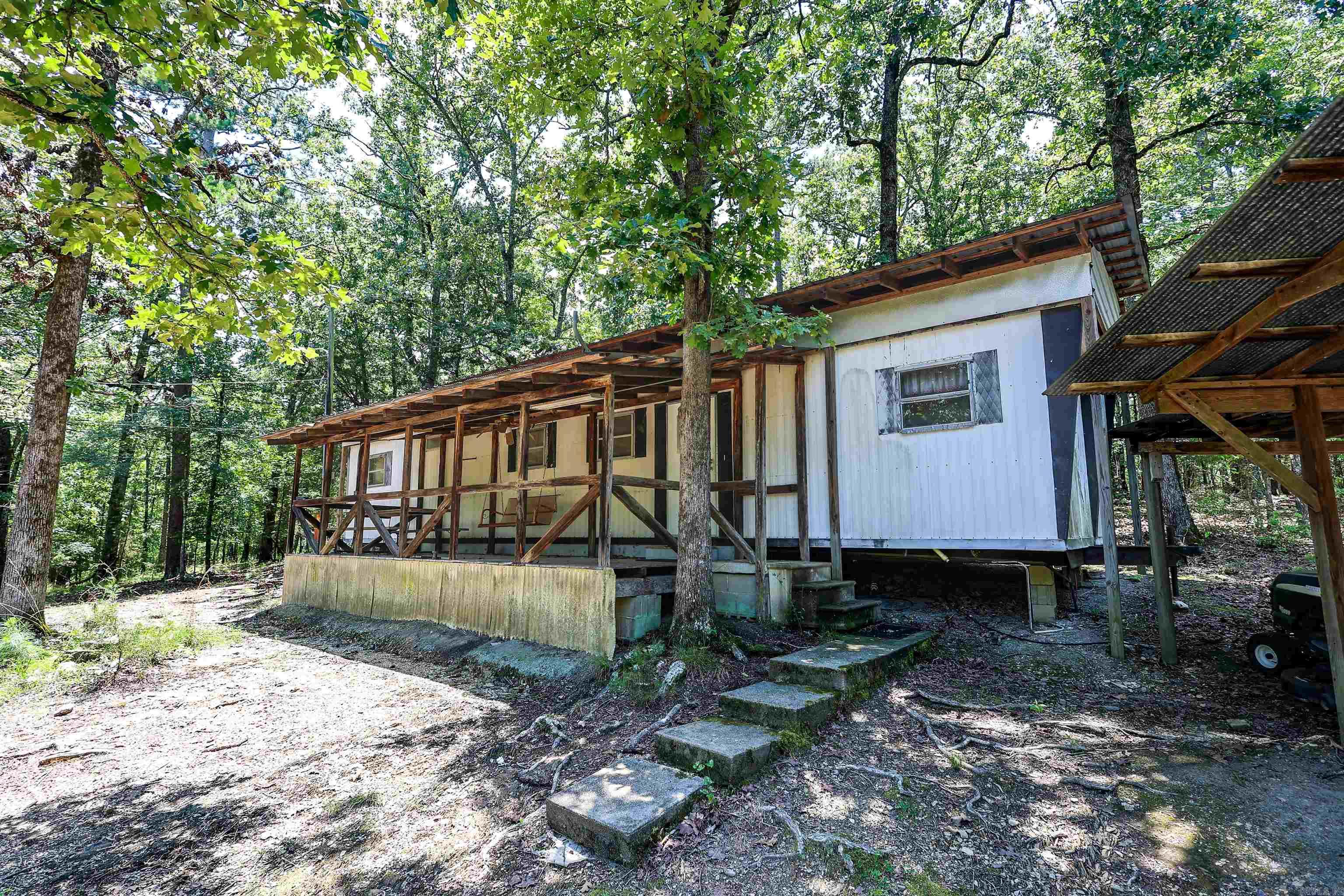 Step back in time with this vintage fishing camp tucked among the trees on 1.08± acres near beautiful Lake Ouachita. Located approximately 1 mile from Little Fir Landing, this 1971 mobile home offers 2 bedrooms, 1 bathroom, and approximately 552± square feet of simple lake-area living.  For years, this property served as a hunting and fishing retreat—a place to launch the boat before sunrise, clean the day's catch, and enjoy the outdoors. Features include a fish cleaning station and a minnow vat with both water and electricity already in place, making it well-suited for anglers and outdoor enthusiasts.  Tucked away and conveniently located near some of the area's best fishing and recreation opportunities, this property offers an affordable opportunity to own a piece of the Lake Ouachita lifestyle. Whether you're looking for a weekend getaway, hunting camp, fishing retreat, or a property to make your own over time, this one is worth a look. Agents see remarks.