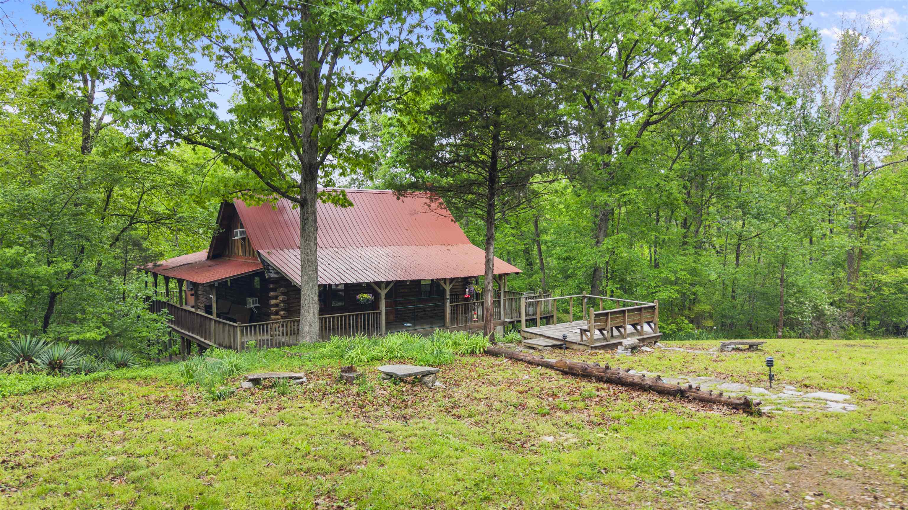 Welcome to 709 Jones Road in Timbo, Arkansas — a fully furnished authentic log cabin tucked away down a quiet dirt road and literally nestled in the mountains of Stone County, where the property stretches across the clear waters of Roasting Ear Creek. This is the kind of place people dream about when they picture a true Ozark escape. Inside, the cabin offers a main-level bedroom plus a two-sided loft that comfortably holds three king beds in total. An enclosed, heated and cooled sleeping porch wraps around the back, creating a year-round retreat surrounded by nature. The kitchen blends rustic charm with modern appliances and conveniences, making everyday living or guest stays effortless. A stand-up crawlspace adds security and practicality, while a hidden ground-level porch gives you one more place to relax, listen to the creek, and enjoy the quiet. Whether you’re looking for a nightly rental investment, a weekend getaway, or a full-time residence, this property delivers privacy, character, and natural beauty — all just minutes from the music, shops, and energy of beautiful Mountain View, Arkansas. All furnishings to be included with acceptable offer.
