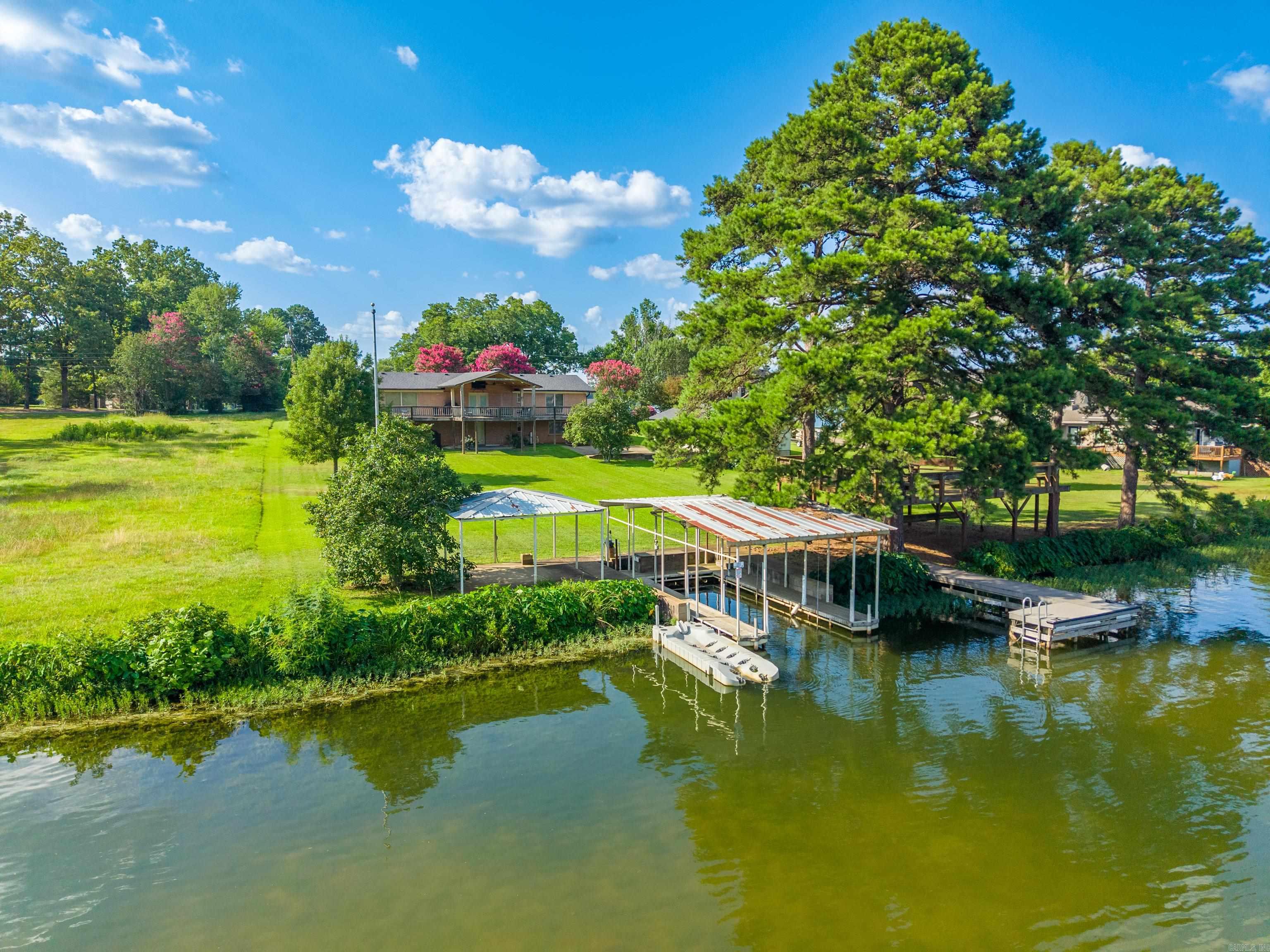 Experience the best of lake living with this beautifully updated home on Lake Hamilton, offering 150 feet of shoreline and a private boat dock complete with a boat lift and jet ski ramp. The traditional exterior is complemented by two spacious lakeside decks, providing the perfect setting for entertaining, relaxing, or taking in the waterfront views.  Inside, you'll find an inviting floor plan with abundant living space and a beautifully updated kitchen featuring quartz countertops. The home offers five bedrooms and three updated bathrooms, with four bedrooms and two baths conveniently located on the main level and a private fifth bedroom and full bath downstairs—ideal for guests or additional family space.  Thoughtfully updated throughout, this property features a new roof (2024), new HVAC system (2024), new gutters (2024), a newly fenced area, sprinkler system, and kitchen appliances that are only three years old. A detached shop provides excellent storage or workspace for hobbies and lake toys.  Currently operating as a successful Airbnb, this turnkey property comfortably sleeps up to 14 guests, making it an outstanding investment opportunity or the perfect year-round residence