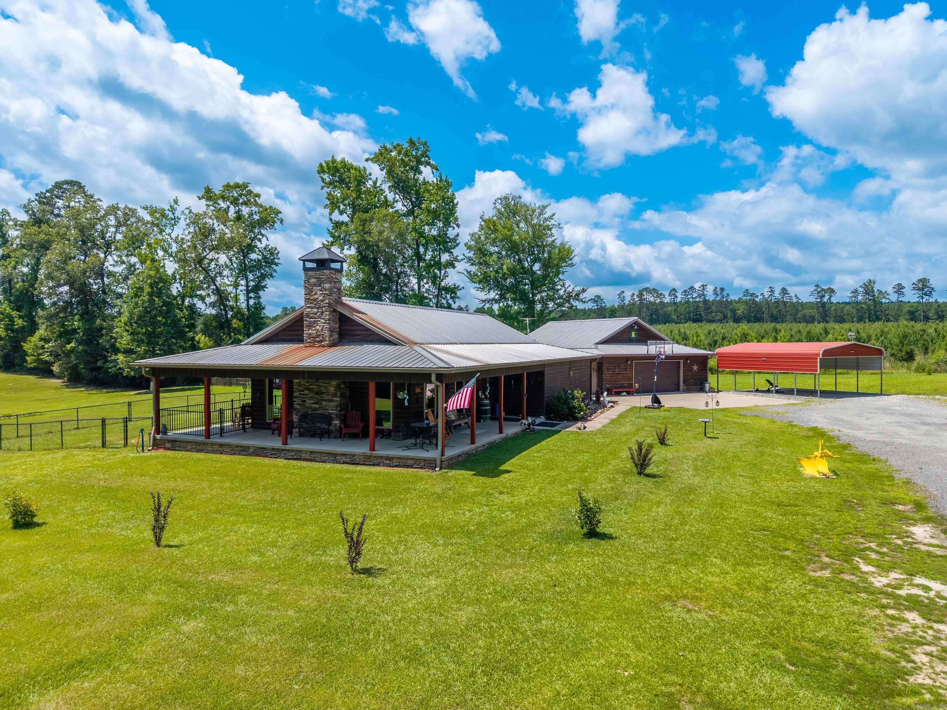 Escape to your own private retreat with this beautifully designed 2 Bed/2 Bath cabin nestled on 9.34 acres. Enter the gated driveway & enjoy the peace, privacy, & charm this one-of-a-kind property offers. The open floor plan is centered around a stunning fireplace, creating a warm and welcoming space to gather w/family & friends. The thoughtfully designed kitchen features a 5-burner gas cooktop, 24-in griddle, & abundant workspace. Stained concrete floors throughout the home provide both durability & timeless style. Spacious primary suite offers a luxurious ensuite bathroom with a clawfoot soaking tub, walk-in shower, and generous walk-in closet. Heated/cooled 2 car garage with safe room/storage shelter, full bathroom & washer/dryer hook up. Perfect for an in-law suite/guest quarters. Step outside to the covered back patio for the ultimate entertaining space w/a custom outdoor bar, perfect for hosting game days or relaxing. Explore the property on the private walking/riding trail that leads to a new bridge & a peaceful picnic area. Additional features include a tankless water heater, whole-home generator, 2 car carport, chicken house, new fencing & freshly painted inside & out!