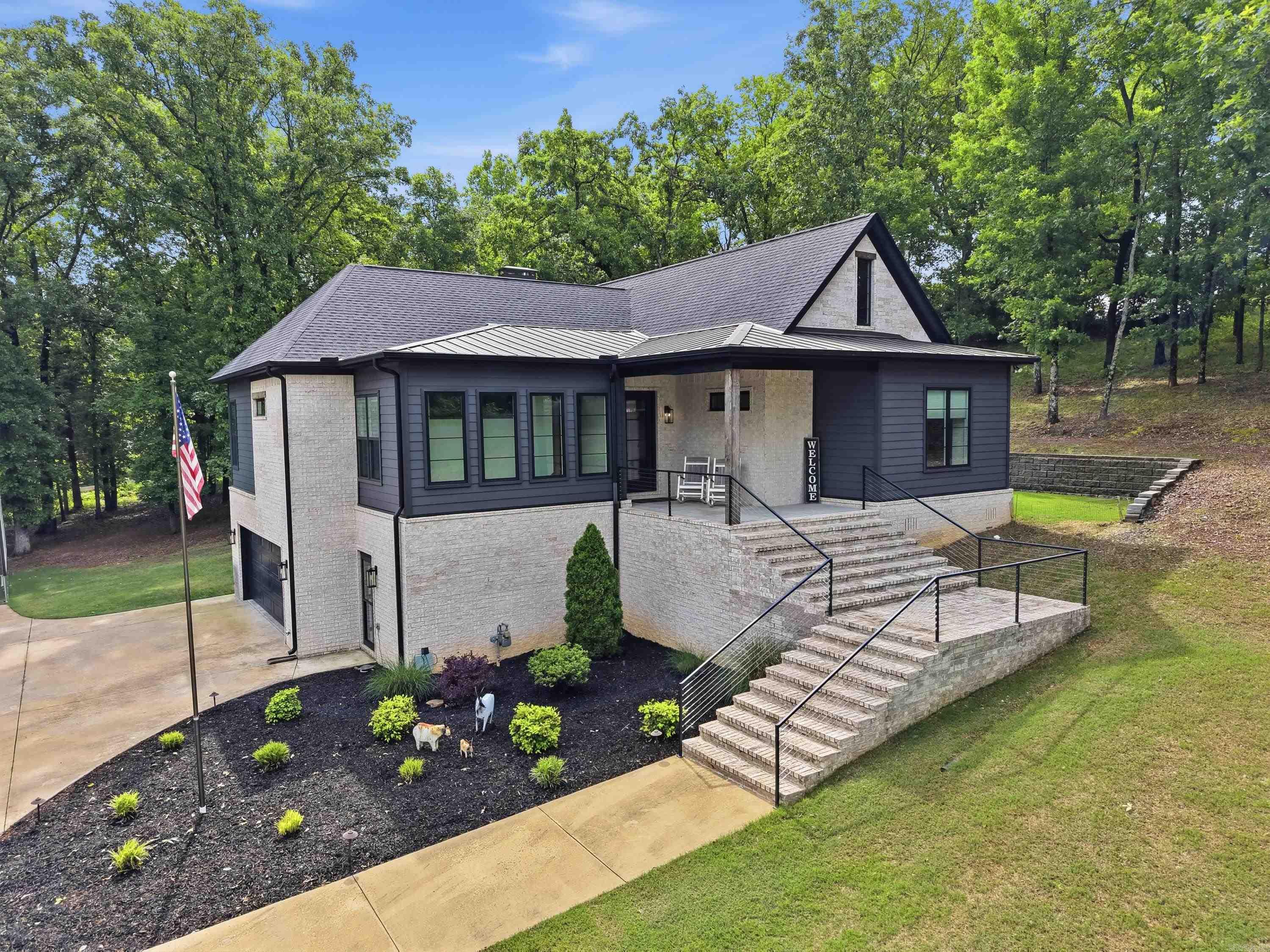 Nestled in the gated community of Point Ridge, this custom-built modern transitional home sits on a private 1.79-acre lot surrounded by more than 100 trees, offering the perfect blend of luxury and privacy. With approx 2,600 square feet, this light-filled home features 3 bedrooms, 3.5 bathrooms, and a built-in F5 storm room for added peace of mind. The striking exterior combines white brick and black Hardie board for timeless curb appeal. Inside, you’ll find custom tile flooring, designer lighting, elevated finishes, and a dramatic steel-framed glass partition with an arched grid design that sets the tone for the home’s unique style. The luxurious primary suite offers a spa-like bath with a soaking tub inside the oversized shower. Additional highlights include a deep 2 car garage, dedicated RV port, and a wraparound porch with an outdoor stone fireplace perfect for relaxing evenings. This one-of-a-kind property offers thoughtful design, exceptional finishes, and an unbeatable location. Agents See remarks.  Square footage approximate, please measure.