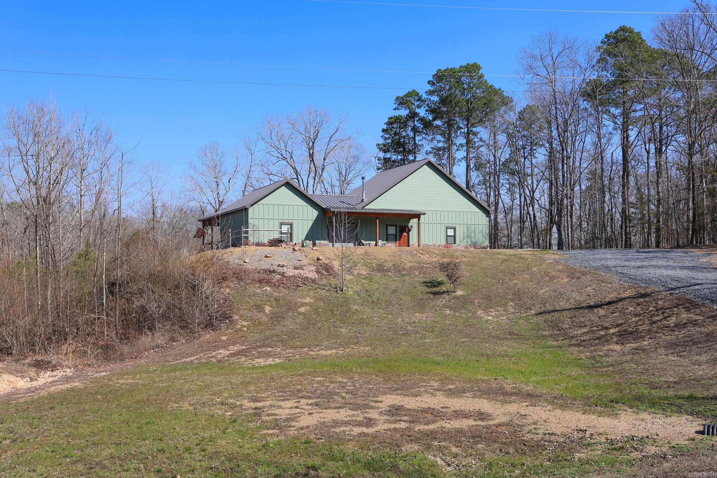 This stunning modern dogtrot home blends rustic charm with contemporary design, offering the perfect blend of privacy and comfort. At the heart of the home is a beautifully designed, enclosed dogtrot, featuring garage doors that open up to create a seamless indoor-outdoor living experience. This home features a complete built-in outdoor kitchen with plenty of room to relax and entertain, while taking in the stunning mountain views and listening to SweetWater Creek below. A separate garage provides space for storage, hobbies or workshop area. Nestled at the foothills of the Ouachita Mountains and just minutes from the Caddo River and the Glenwood Country Club. This well thought out floor plan and exceptional craftsmanship are a must see.