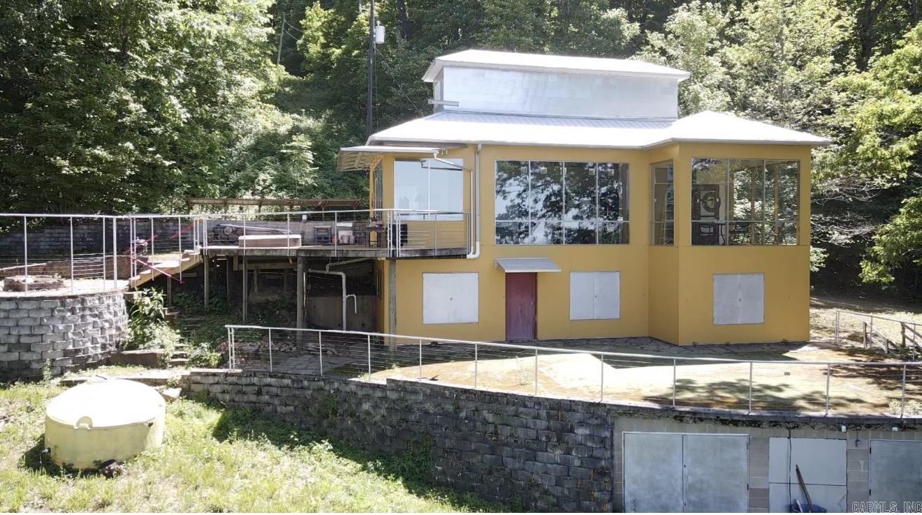 Escape to this one-of-a-kind, architect-designed retreat offering breathtaking mountain views and unmatched privacy, bordered by National Forest on two sides. A dramatic wall of floor-to-ceiling windows spans the upper level, capturing a stunning 25-mile panoramic view. These upgraded stainless steel, double-paned windows extend into a renovated sunroom with R-30 ceiling insulation. The property features a spacious workshop, two wells (condition unknown), and extensive recent upgrades, including new deck boards (2026), HVAC system and whole-house dehumidifier (2024), and an improved, widened driveway (2023). A rainwater collection system with UV and particulate filtration adds sustainability. Inside, new appliances—including a washer, dryer, and dishwasher—make the home move-in ready. Hurricane Creek runs through the land, which is rich with wildlife, waterfalls, and unique geological features. Located near the St. Francis National Forest, a designated USFS Special Interest Area, the property also offers direct access to the Blue Hole Cascades hike. Ideal as a private residence or getaway, this award-winning home delivers a rare blend of design, nature, and tranquility.