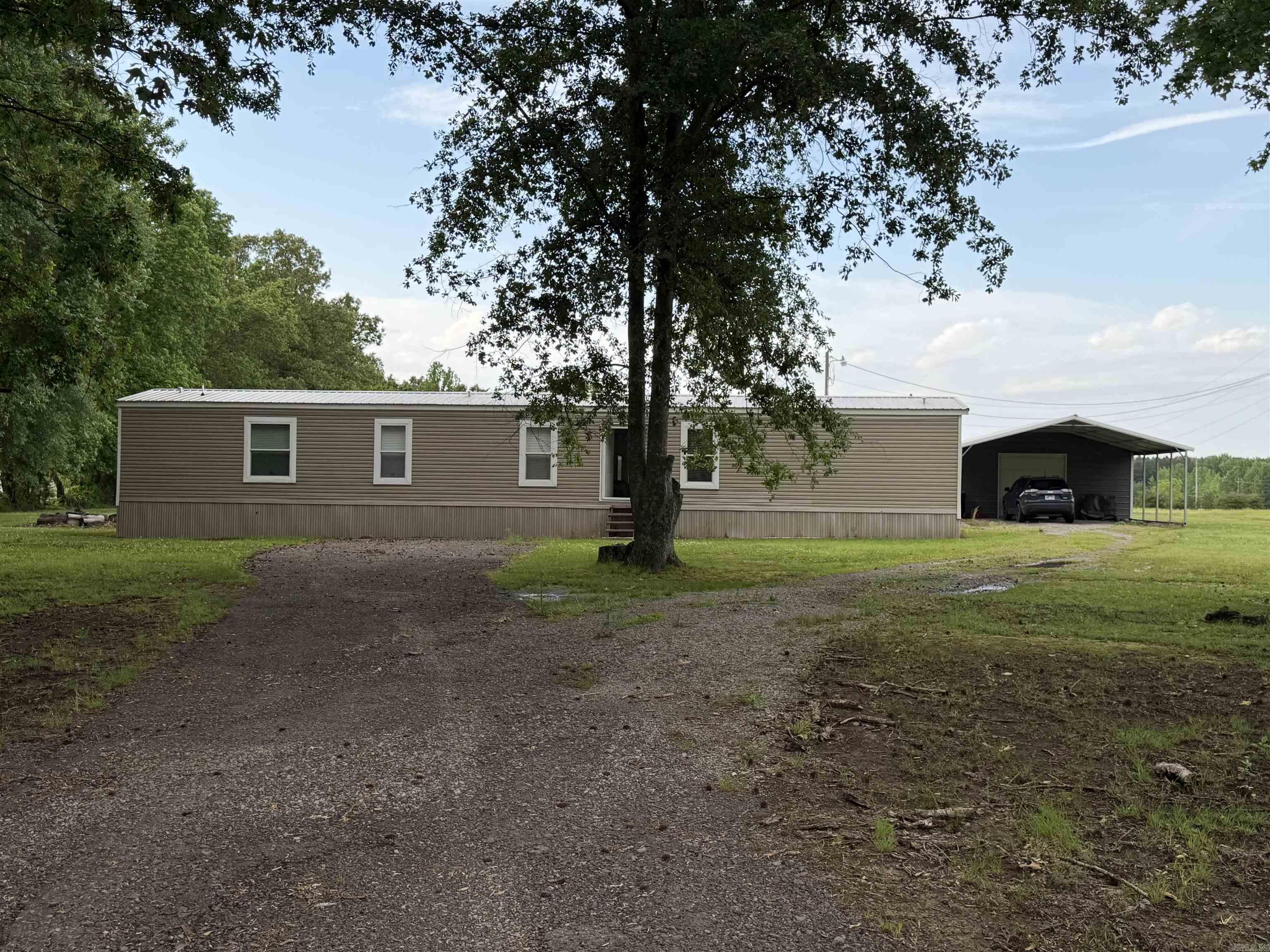 Welcome to peaceful country living with modern comfort! This like-new 2023 mobile home offers 1,216 sq ft of well-designed space on a beautiful 1-acre lot. Step inside to an inviting open layout featuring luxury vinyl flooring throughout the main living areas and carpeted bedrooms for added comfort. The kitchen and living area flow seamlessly, perfect for everyday living or entertaining, with plenty of natural light creating a warm, welcoming feel. Enjoy your morning coffee or unwind in the evenings on the 8’x10’ covered back deck, overlooking your spacious property. Outside, you’ll find a paved driveway leading to a 24’x25’ shop—ideal for hobbies, storage, or workspace—plus an attached 20’x24’ carport providing ample covered parking. If you’re looking for a move-in-ready home with modern finishes, functional outdoor space, and room to breathe, this one checks all the boxes! On a PERMANENT FOUNDATION.