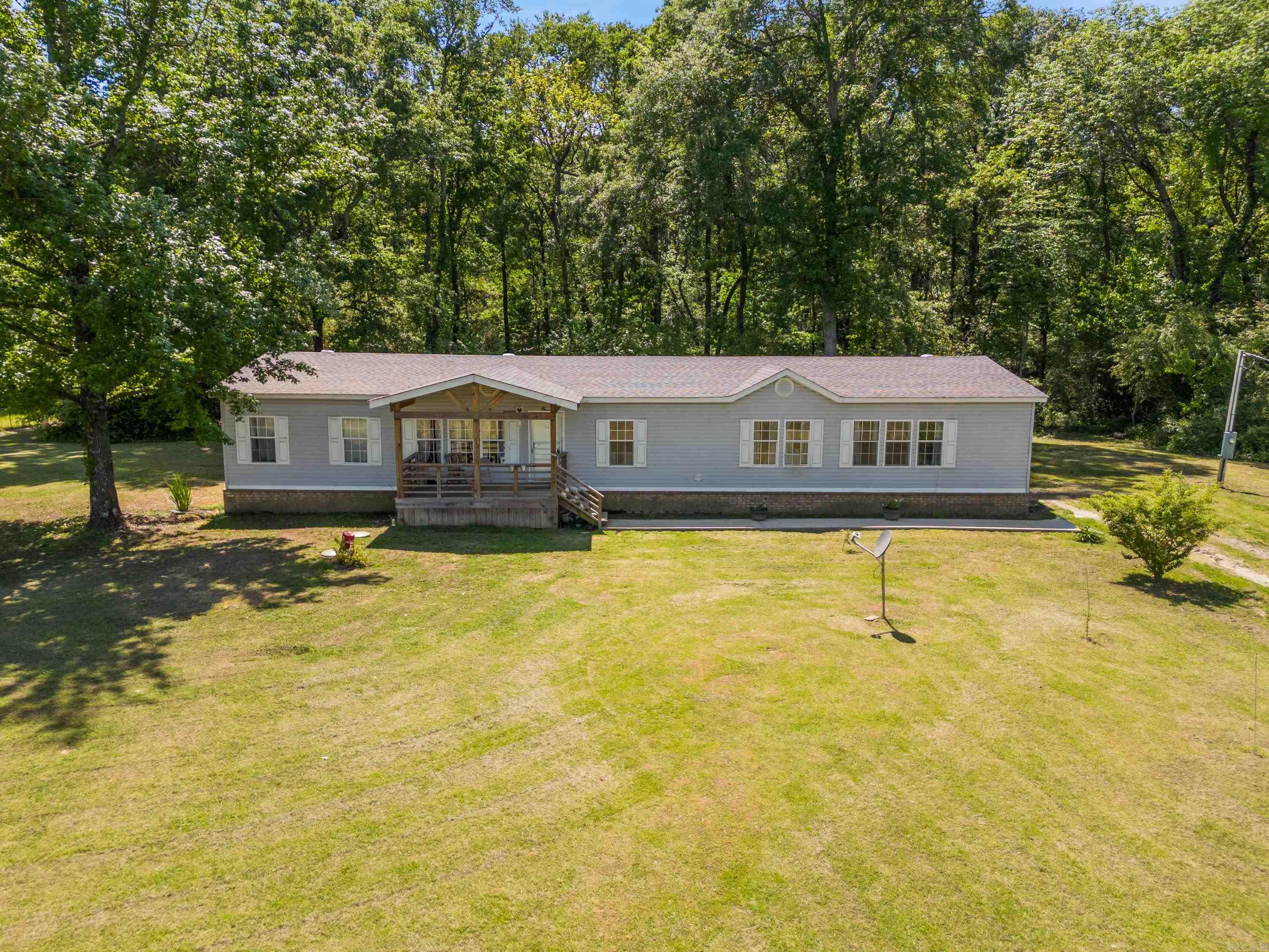 Tucked away on approximately 7 acres, this property offers the perfect blend of open space and wooded privacy, complete with a creek. A newer outbuilding provides additional space for storage, hobbies, or a workshop. Inside, you'll find 4 bedrooms, 2 baths, two living areas, a cozy fireplace and an open floorplan designed for comfortable living. The spacious primary suite includes an oversized closet and a large bath. Whether relaxing on the covered front porch or enjoying the peaceful surroundings, this home invites you to slow down and take it all in. Roof was replaced approximately 5 years ago! Washer, dryer and refrigerator convey. AGENTS please read information in remarks!!