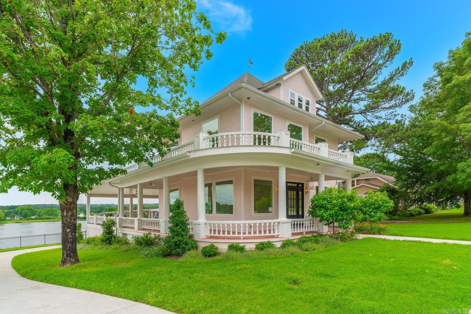 Perched high above the Arkansas River in Ozark, this beautifully restored 3,800 sq. ft. historic home offers some of the most breathtaking panoramic views in the Arkansas River Valley. Built in 1924 and completely remodeled, every area has been tastefully updated with all-new plumbing, wiring, and high-end finishes while preserving the home’s timeless character.  Designed for entertaining, the home features an easy flow from the welcoming front entry through expansive open living spaces to the oversized rear veranda, where sweeping river, bridge, and sunset views create an unforgettable backdrop. Large windows throughout the home capture the beauty of the river from nearly every angle, filling the home with natural light and spectacular scenery.  Rich in local history, the attic once housed the ferry captain who oversaw the Arkansas River ferry operation. Cozy nooks, private spaces, delicate touches of pink, two laundry rooms, and spacious living areas provide comfort and charm throughout.  Ideally located about an hour from Fayetteville and centrally positioned between Little Rock and Oklahoma City, with easy access to Dallas and Kansas City.