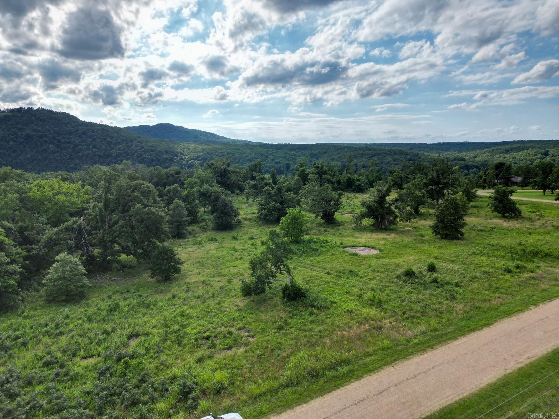 Discover 7.75 acres of mostly level Ozark beauty in White River Valley Subdivision near Mountain Home, AR. Surrounded on three sides by paved county roads, this versatile tract offers excellent access, mature hardwood trees, and minimal dirt work for your future homesite. Plenty of room for a home and spacious yard, with potential to subdivide subject to community restrictions. A unique feature is the possibility of creating a drive-through driveway with county road access on opposite sides of the property. Electricity is available at the road; private well and septic required. Enjoy subdivision amenities including a community boat ramp and clubhouse on the White River. Located just minutes from Cotter, the Trout Capital of the World, and near Norfork Lake, Bull Shoals Lake, the Norfork River, Buffalo City, and multiple White River access points including Wildcat Shoals, Roundhouse Shoals, Rim Shoals, and Cartney Access. Annual HOA fee and protective covenants apply.