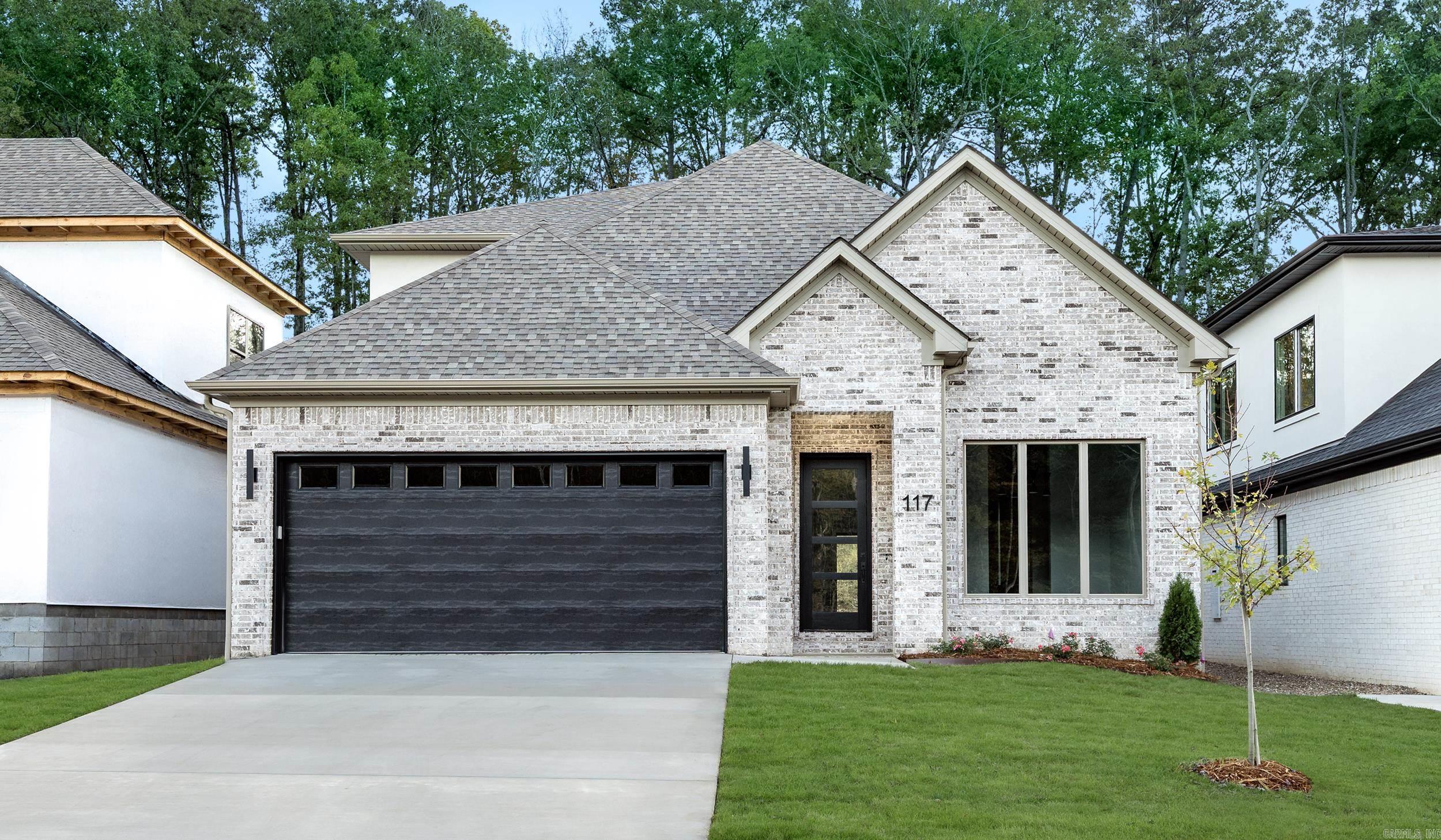 Welcome to 117 Kinley Loop, a beautifully designed home where sophisticated style meets everyday livability. The warm neutral brick exterior and unique designer light fixtures set the tone for the refined details you’ll find throughout. Inside, the open floor plan connects a stunning kitchen with double islands to a formal dining room and inviting living area anchored by a sleek black fireplace. Expansive sliding glass doors open to a covered patio—perfect for entertaining or relaxing outdoors. The primary suite is a luxurious retreat featuring a soaker tub, large glass shower, and designer finishes that make every day feel like a spa day. A double-sink vanity and expansive closet offer both comfort and convenience. A large laundry room and thoughtful layout make this home as functional as it is beautiful. Upstairs, you’ll find two additional bedrooms joined by a Jack-and-Jill bath with a separate toilet and shower area for added privacy. Blending modern design with timeless warmth, 117 Kinley Loop is a home that feels both sophisticated and inviting.