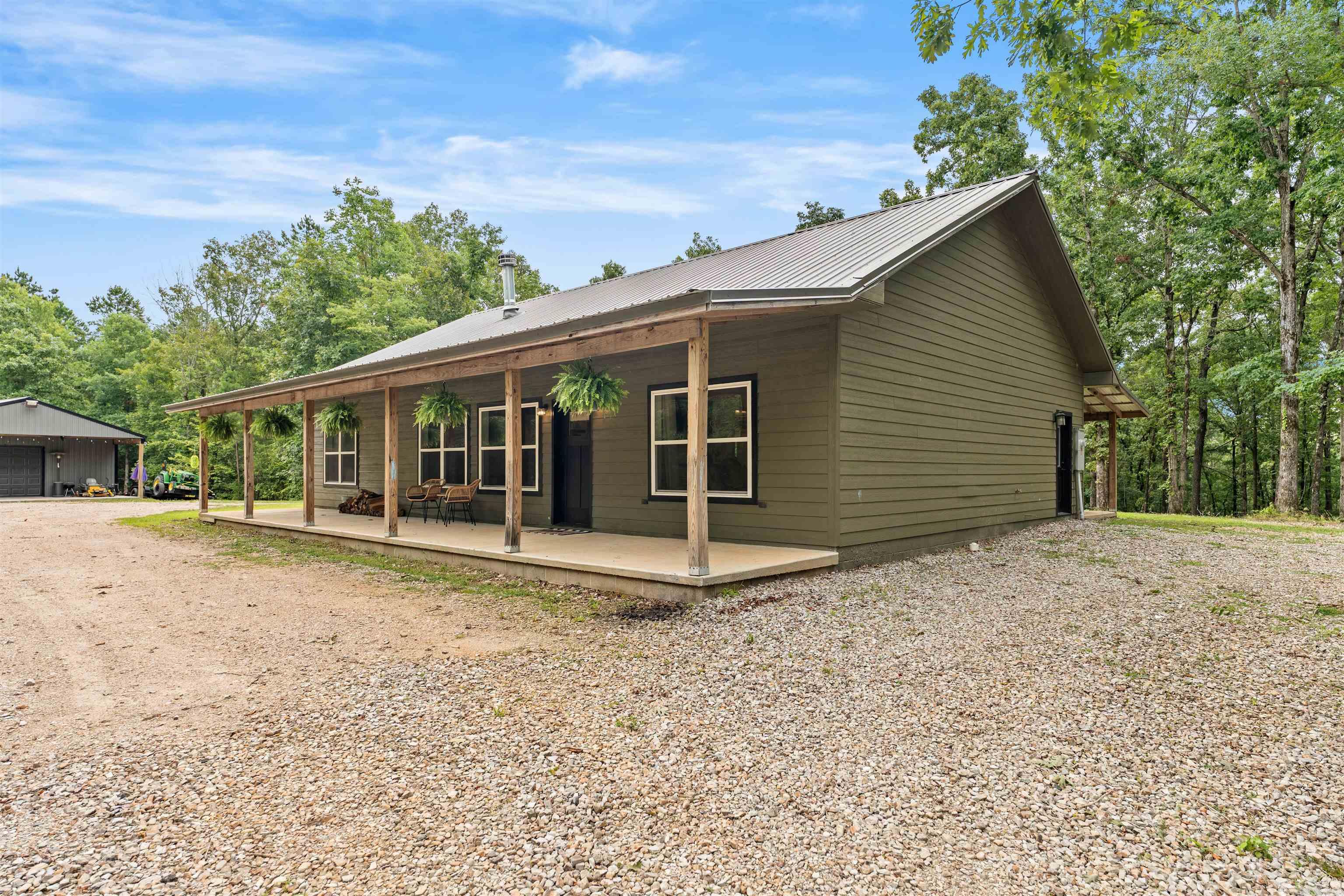 If you've been looking for a place where you can truly get away from it all, this is it. Built in 2024 and tucked behind a private gate with no neighbors in sight, this home is the kind of peaceful you can't find just anywhere. The split floor plan is open and airy. Finished concrete floors run throughout, and the wood-burning fireplace with custom built-ins on either side makes the living area feel like the perfect place to settle in. The kitchen checks all the boxes granite countertops, an island with seating, a gas cooktop, and a walk-through pantry. And doing the dishes gets a little more enjoyable when you can watch the wildlife right out your kitchen window. Step outside and enjoy your morning coffee or evening sunsets on the large front and back porches. The 40x50 shop with electricity and its own bathroom is ready for whatever you need - equipment storage, a workshop, or just room to spread out. This kind of privacy doesn't come up often. Come take a look.