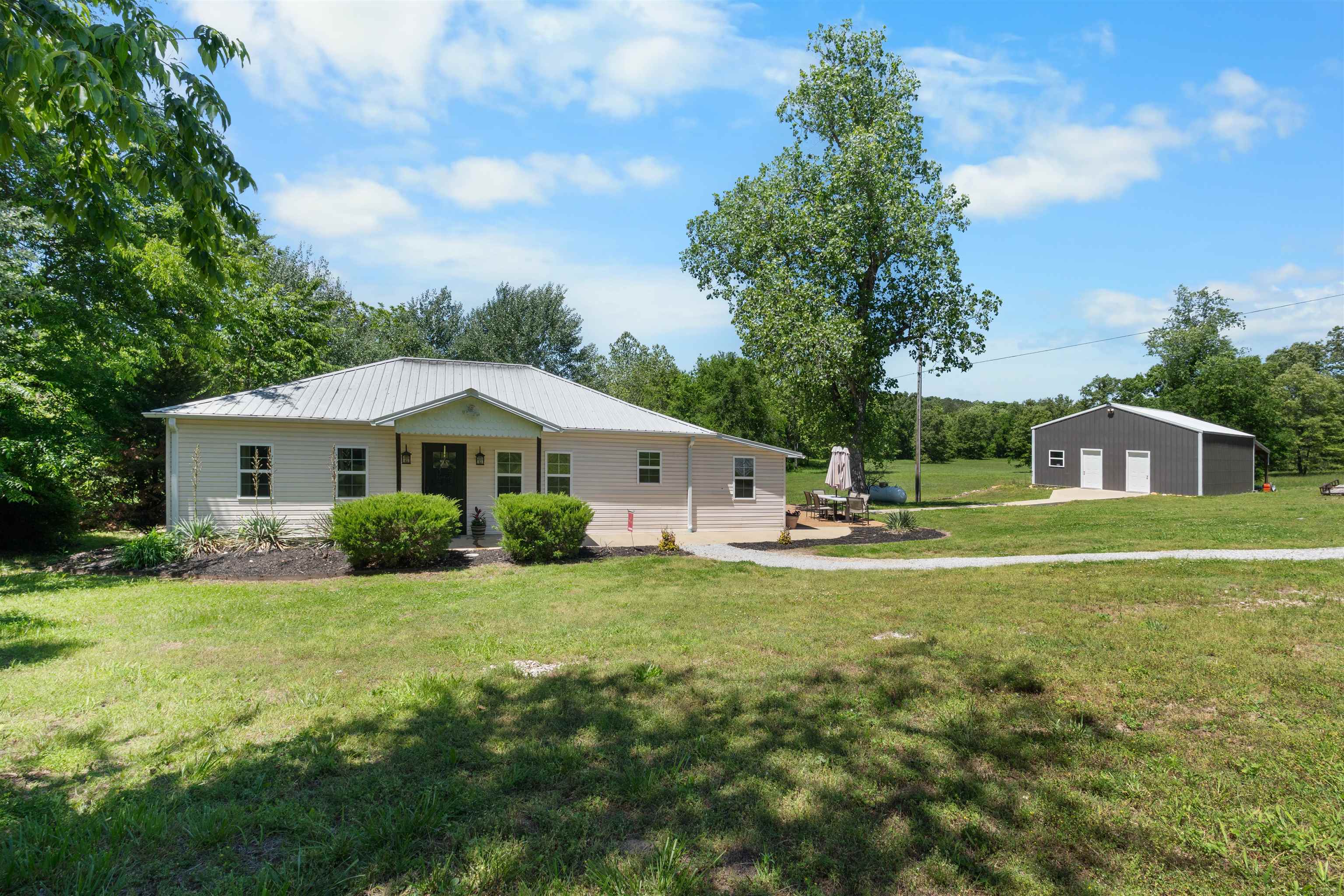 This beautiful 2 bedroom, 2 bath home offers the perfect blend of comfort, functionality, and country charm. Situated on 13.1 gorgeous open acres with a year-round creek. Inside, you’ll love the open floor plan featuring a spacious living area with a gas fireplace. The kitchen has custom hickory cabinets, a breakfast bar, and an open flow into the dining area. The master suite includes an attached full bath with a walk in tile shower. The guest bedroom is spacious with easy access to another full bathroom. The mudroom/utility area offers fantastic space for an office or 3rd bedroom option.  Outside is a back patio, a 32x26 shop fully insulated with a finished out area complete with a full bathroom, plus a garage/workshop space with a lean to attached for additional storage.  With all open usable acreage, stunning pasture views, and a year-round creek running through the property, this one of a kind property is perfect for a hobby farm!