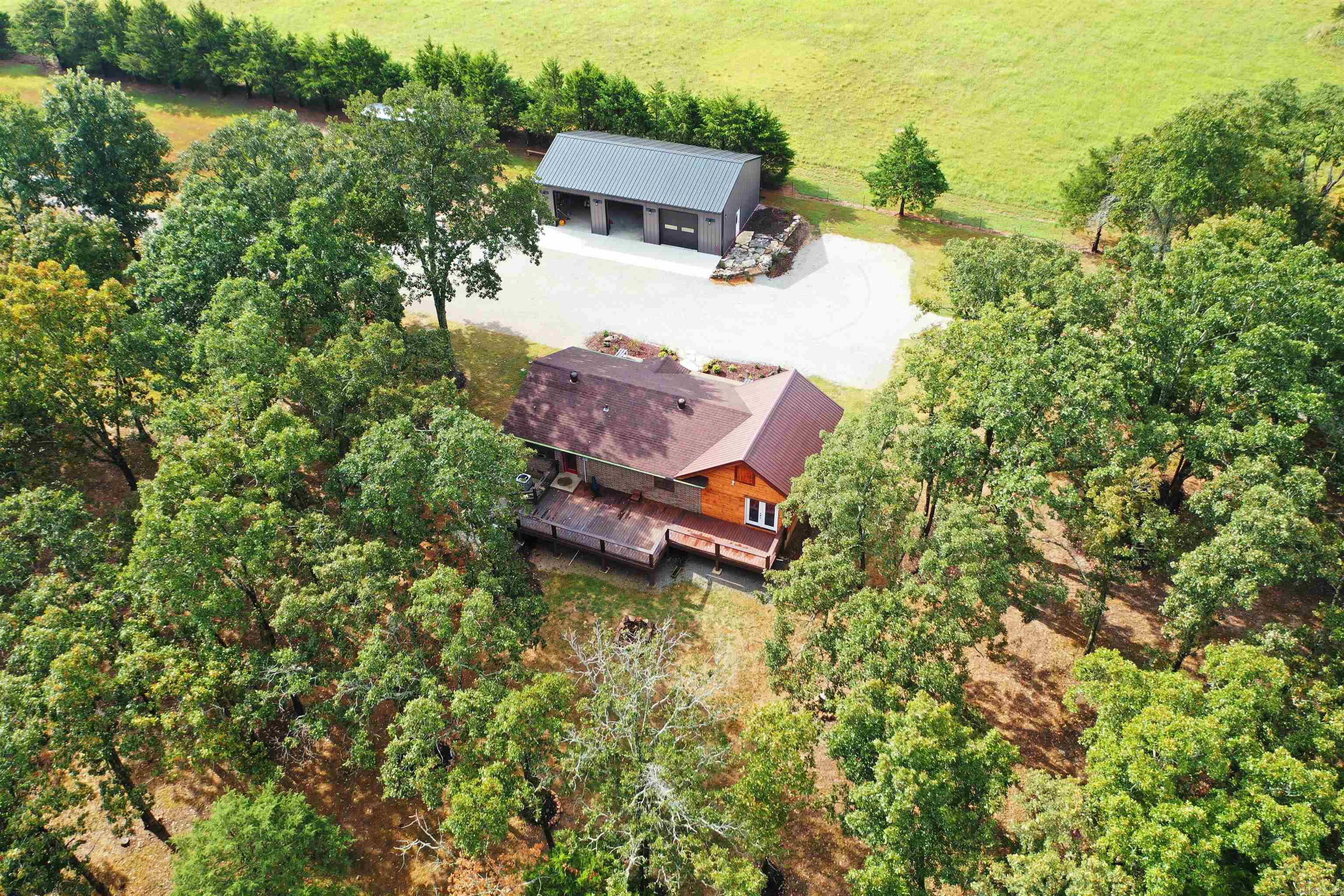 Escape to 80 acres M/L just 3 miles from the Lake Norfork Boat Ramp & minutes to town. Brahma Trail Ranch offers open pastures, wooded acreage, & complete privacy on a paved county road in a welcoming farm community. Enjoy lake life with this 3-bedroom, 2-bath home featuring a luxury master suite, French doors to a massive 16x45 porch overlooking rolling land, mature trees, & a cozy fire pit. A 30x50 shop with three 10x10 doors, power & water, plus an additional 30x20 shop, provides ample space for hobbies, storage, or a home business. Multiple building sites offer potential for a family compound or guest homes. Open pastures are ideal for horses, cattle, or farming, while wooded areas provide excellent hunting & privacy. Two creeks run along the North & NW boundaries with pond potential. Several recent improvements listed in additional documents. Income potential with fishing cabins or rentals. Listed at $1,149,000
