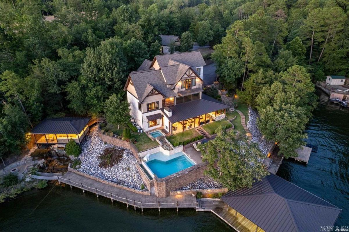 Situated on a majestic seven-acre estate, this extraordinary one-of-a-kind retreat boasts unparalleled luxury and breathtaking views of Lake Hamilton's serene waters. This custom-built masterpiece, completed in 2016, spans over 8,100 square feet and features six bedrooms, five bathrooms, and exquisite finishes. The open floor plan is perfect for grand gatherings, with seamless transitions between the gourmet kitchen, dining area, and lavish living room. Entertainment spaces are in abundance, including a private theater, outdoor kitchens, bunk bed room, and a sparkling pool surrounded by panoramic lake views. Enjoy direct access to the lake with almost 500' of waterfront with four private boat docks, perfect for boating, fishing, or simply soaking up the sun. Luxury details are evident throughout, from designer lighting to high-end appliances, fine finishes, and tasteful furnishings. The property also features a detached garage, ideal for car enthusiasts or hobbyists, offering the potential for conversion into a second dwelling. Secure boardwalks and stunning waterfall features enhance the estate's natural beauty, creating a tranquil oasis. A treasure of luxury lakefront living!