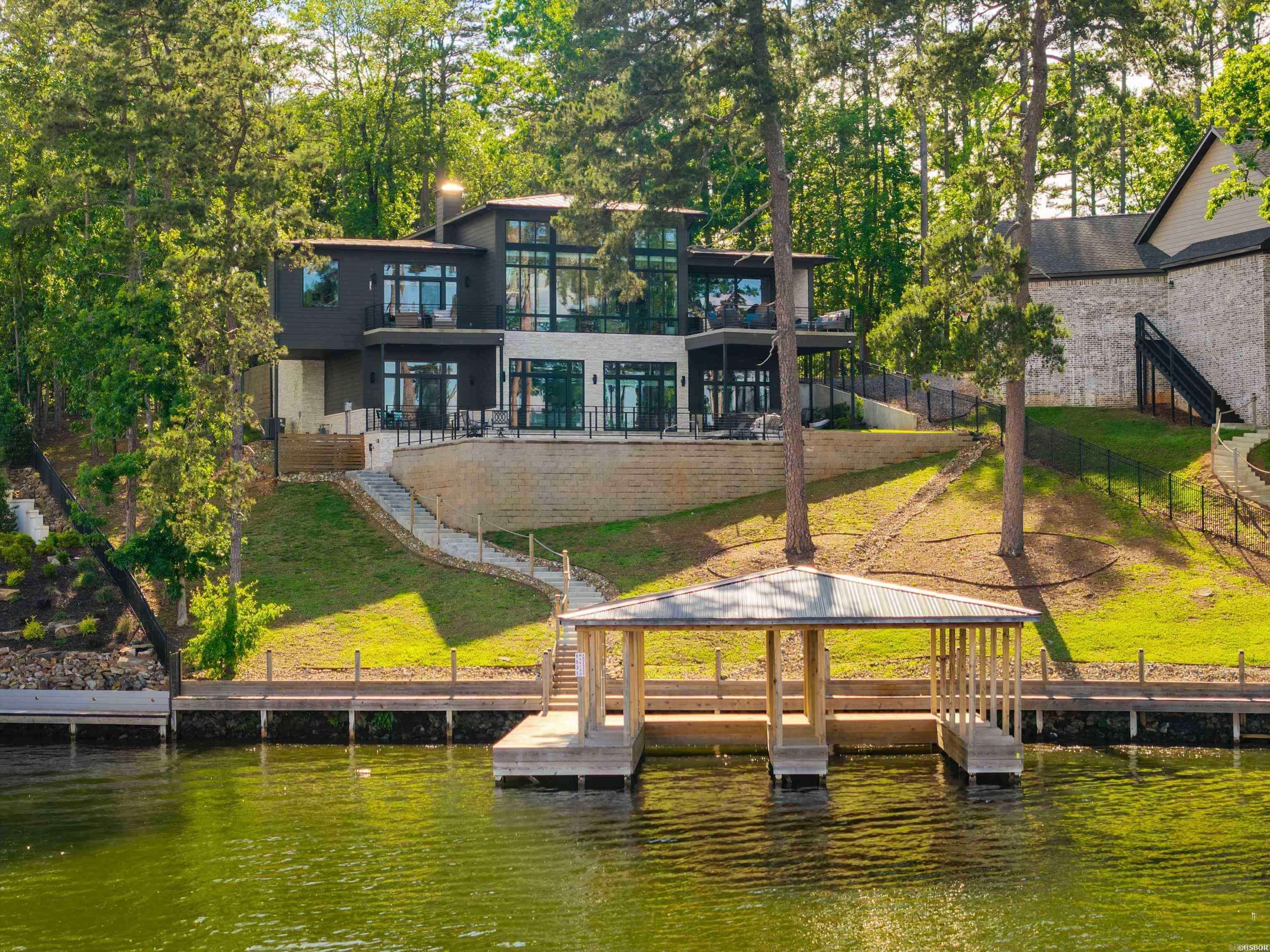 A rare opportunity to own one of the premier properties on Lake Hamilton! This newly built custom home sits on approximately one acre with jaw-dropping lake views and a level of design rarely seen in this market. Bold contemporary architecture, soaring ceilings and massive commercial-grade windows create a dramatic showcase of water from nearly every room. Offering 5 bedrooms & 5.5 baths, the home was built for both luxury living and unforgettable entertaining. Features include a stunning chef’s kitchen, elevator, swimming pool, 3-car garage and a two-stall covered boat dock. The eastern-facing orientation delivers incredible sunrise views without the harsh afternoon heat. And no short-term rental restrictions!  If you're looking for a trophy property on Lake Hamilton, this one's for you.