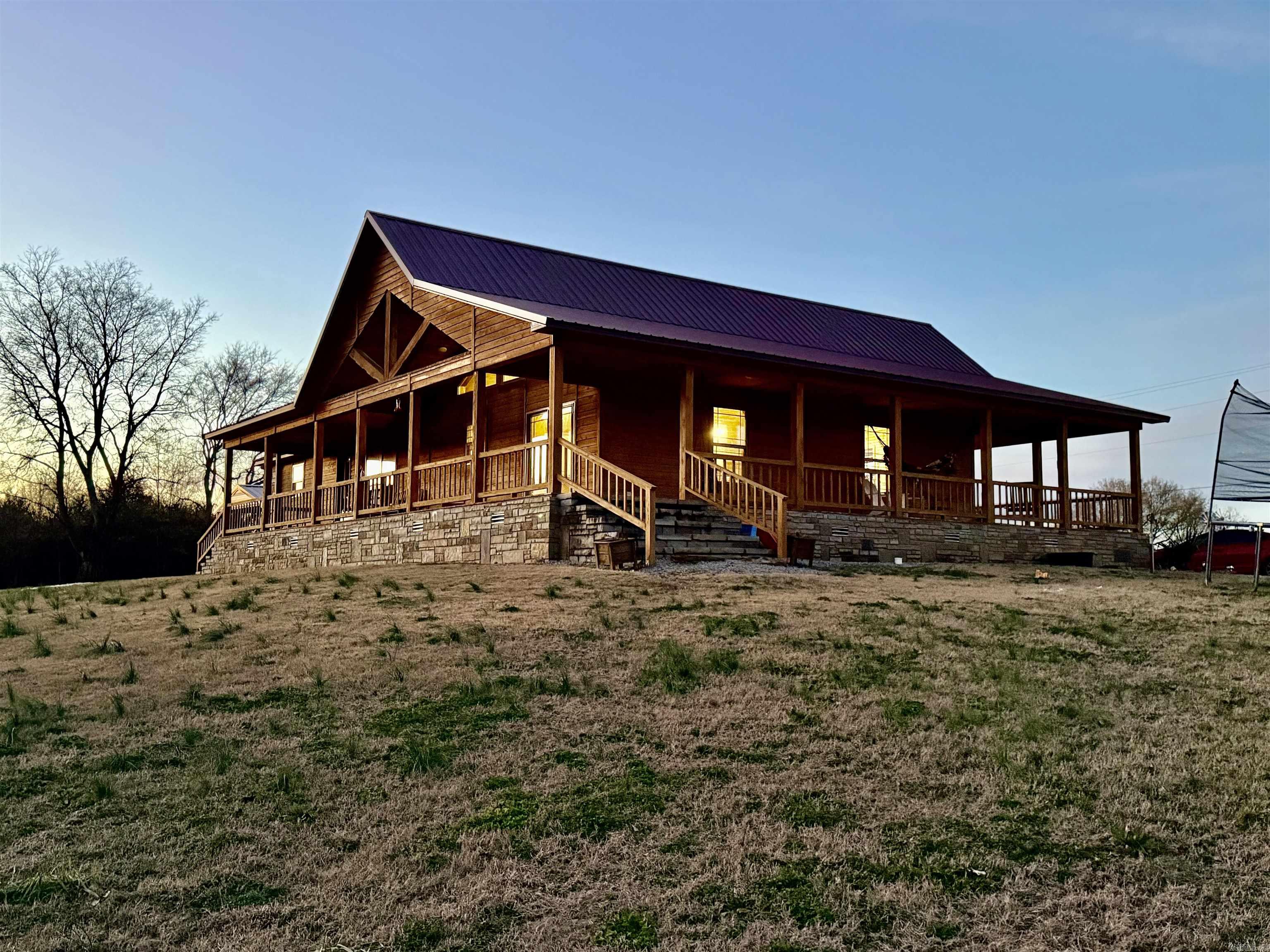 Stunning Country Living Home on 4.68 Acres with Generator, Outbuildings & RV Hookups!   Built in 2021, this beautiful 3-bedroom, 2-bath cedar home offers 1,848 square feet of well-designed living space on 4.68 acres. Featuring an open-concept floor plan, the home is filled with natural light and provides a warm, inviting atmosphere throughout.  Enjoy outdoor living on the full wrap-around porch, perfect for relaxing, entertaining, or taking in the peaceful surroundings. The home is all-electric with a propane backup and is equipped with a 24KW Generac whole-house generator, providing comfort and reliability year-round.  The property is partially fenced for livestock and includes multiple versatile outbuildings. A 420 sq ft enclosed metal shed offers ample storage or workspace, while the attached 700 sq ft covered RV bay adds exceptional functionality. Additionally, a 120 sq ft finished wood-frame shed includes water, electric, septic, and a 100-amp RV hookup—ideal for guests, hobbies, or extended stays.  This property offers the perfect blend of modern construction, rural charm, and practical amenities—an excellent opportunity for those seeking space, self-sufficiency, comfort!!