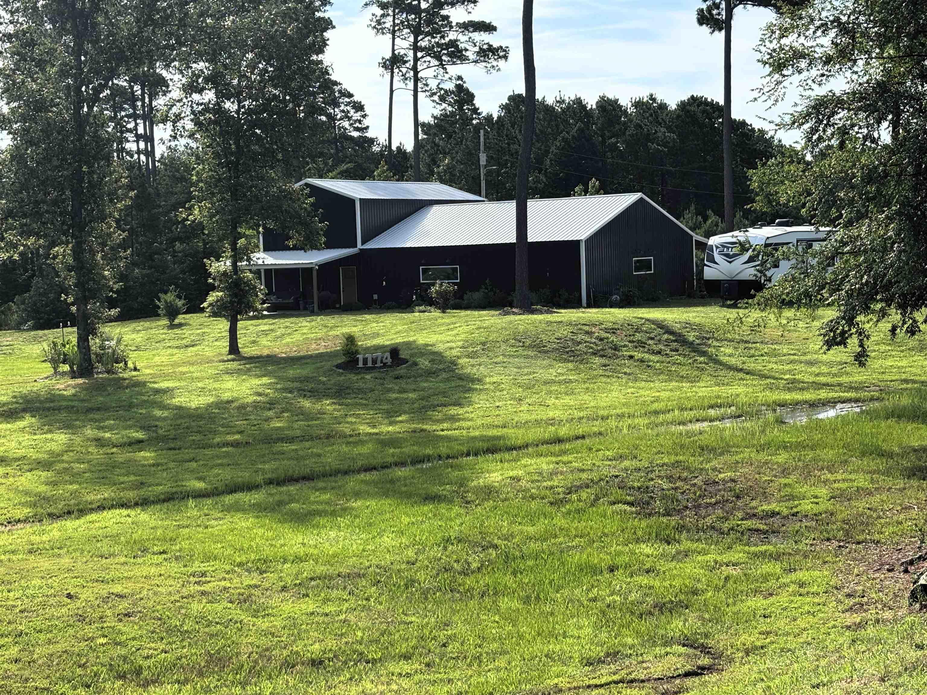 Wide-open views and one-of-a-kind living await in this spacious barndominium on 1.5 unrestricted acres! With 2,960 square feet, 2 bedrooms, 2.5 baths, and two kitchens, this property is designed for comfortable living and entertaining, with room to accommodate 50+ guests.  The upstairs master suite features 800 square feet, a walk-in closet, and a nice walk-in shower. while the main living areas showcase beautiful double v groove pine shiplap walls and sharp black metal siding for a modern country look. The main kitchen is full of personal touches; the pictures speak for themselves. The enjoy high-speed fiber internet, a walk-in pantry, low average electric bills of about $200/month, and propane already stubbed into the living room if needed.  Outdoor features include a 60x12 back porch, 20x12 front porch, greenhouse, garden area, extra landscaping, and full camper hookups with its own septic. A new survey is available. Unique, spacious, and full of character—what a cool place!