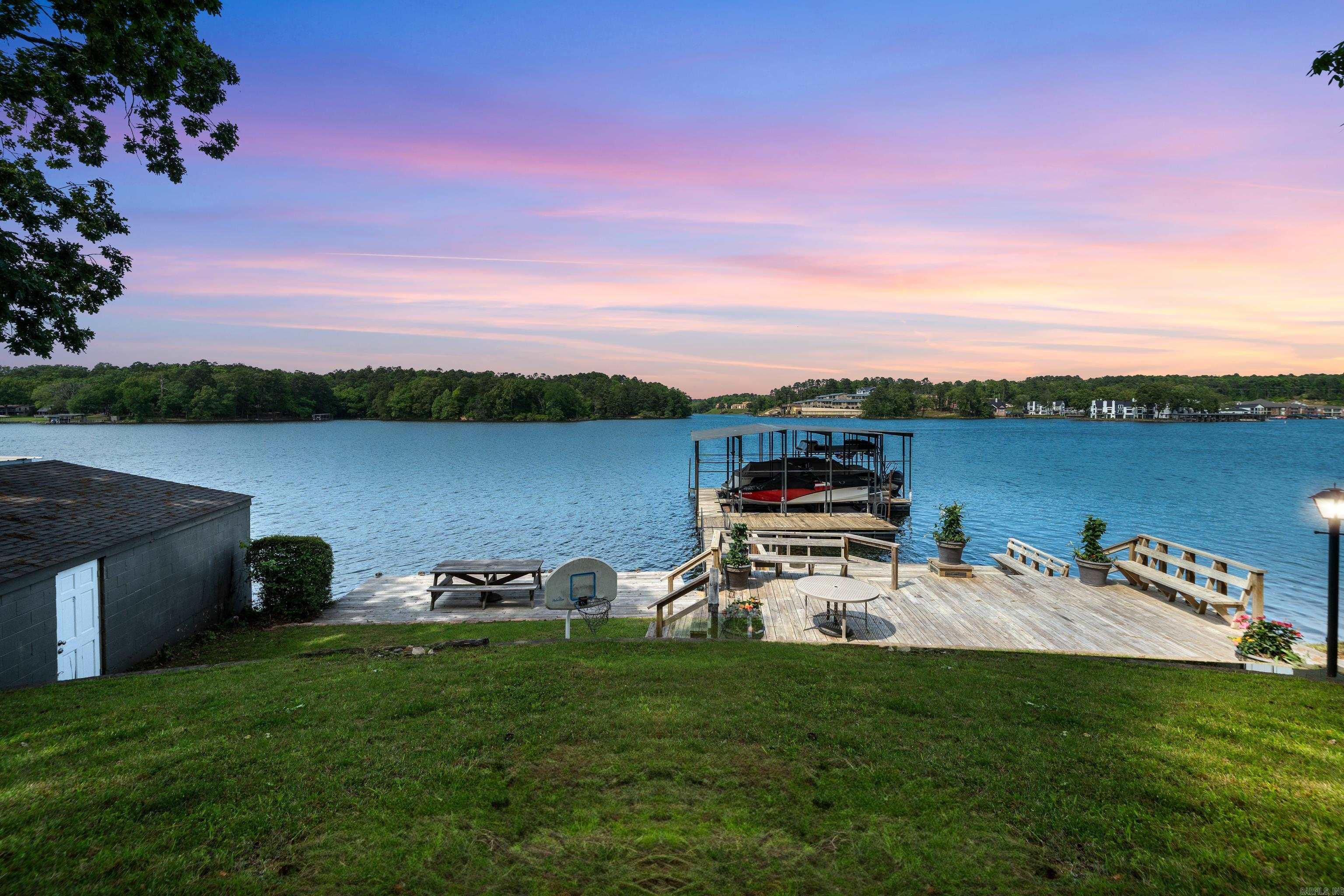 Location, Location, Location! Desirable neighborhood and cove off of Carpenter Dam Rd. close to shopping, Oaklawn, Garvan Gardens and all of the things Hot Springs has to offer!  4 bedroom, 2 bath split bedroom floor plan. Large Living/Dining combo with large windows overlooking Lake Hamilton. Mulptiple Outdoor entertaining. New hot tub (and decking around hot tub) being installed. This has been a wonderful family retreat! Perfect timing for Summer, make this home yours, short term rental, or buy for lot value and build your dream home. 2 boats slips (one oversized) with awesome swim areas and original boat house. One level. Furnished. Dont miss this opportunity!!