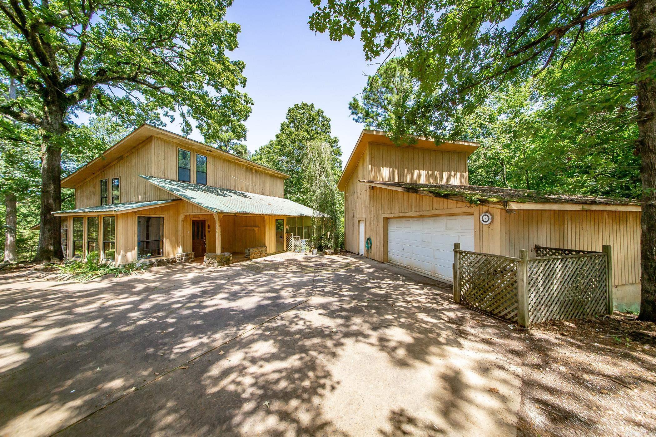 Just 3 miles from the Point Cedar boat ramp on DeGray Lake, this unique property offers incredible short-term rental and future development potential. Situated on 6.5 acres, the custom-built home features 2,225 sq ft, 2 bedrooms, 2.5 baths, a wood-burning stove, sunroom, large pantry, and wraparound screened porch.   A second homesite with septic already installed provides an excellent opportunity for an additional cabin, guest house, or future rental. With plenty of room to expand, investors can explore adding more cabins, RV sites, or other income-producing accommodation.   The property also includes a 22x35 garage/workshop, fenced backyard, and matching LVP flooring for the upstairs. Minutes from boating, fishing, and recreation, this is a rare chance to own acreage near Lake DeGray with room to grow your investment. Whether you’re looking for a vacation rental, family retreat, or future development opportunity, this property checks all the boxes.