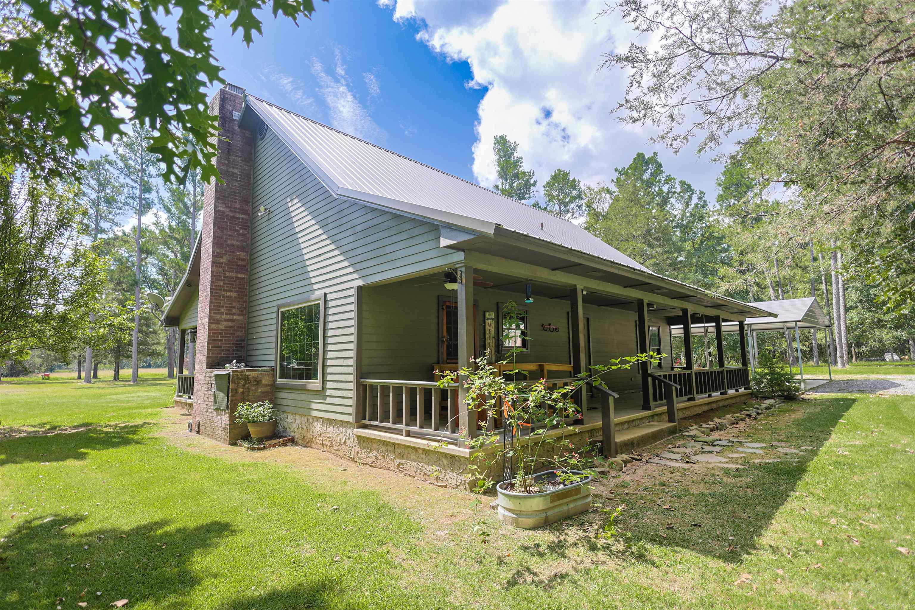 Situated on 5.78 +/- acres in the Lakeview Estates subdivision, this 1.5-story home offers 1,832 +/- sq ft, 3 bedrooms, and 2 bathrooms. The main level includes two bedrooms, while the upper-level loft serves as the third bedroom and features two closets. Built in 2000, the home features a metal roof, Hardie® siding, a freestanding cast iron wood-burning stove, step-free entry and accessibility features, and covered front and back porches. Outside, you'll find a 30' x 40' metal shop with a concrete floor and two 12-foot lean-tos, a 26' x 30' carport, a 140-foot well, and a 1,000-gallon septic system. Conveniently located near Lake Ouachita and the Ouachita National Forest. Hot tub does not convey with the sale. Schedule your private showing today.