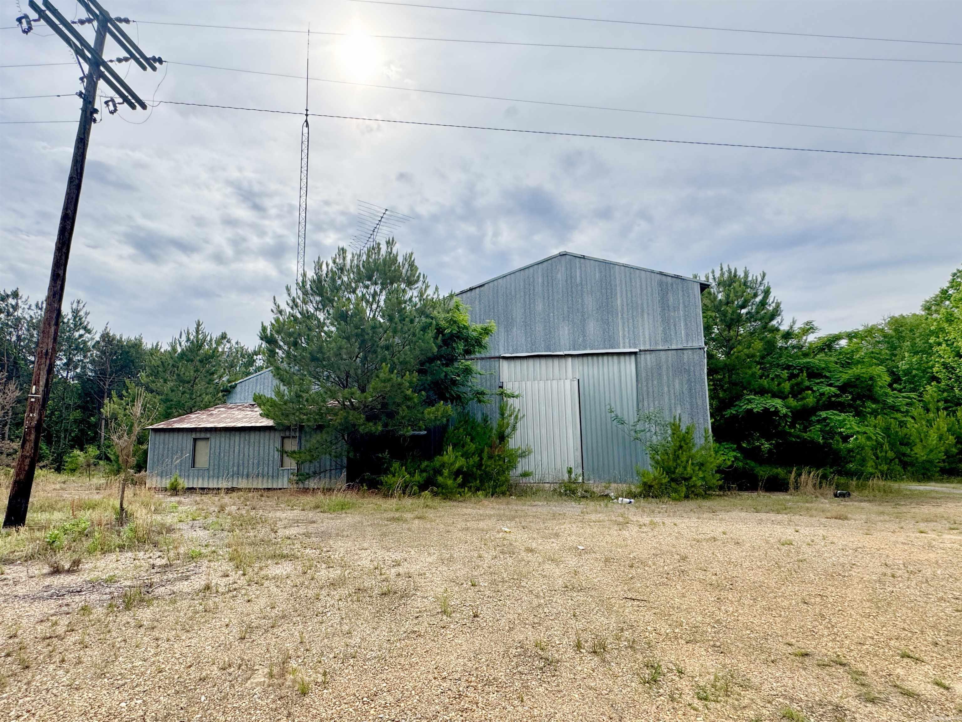 Located on ideal highway frontage, this unique property offers versatile interior and exterior space! Over 10,000 sq ft of slab workshop sits on 17+ acres with gravel perimeter and three large shop doors.  While this property will need a fresh start and some TLC, the location and amenities are hard to find. Seller will give priority to a buyer that will move forward with a as-is sale. Clean title awaits the new owner!