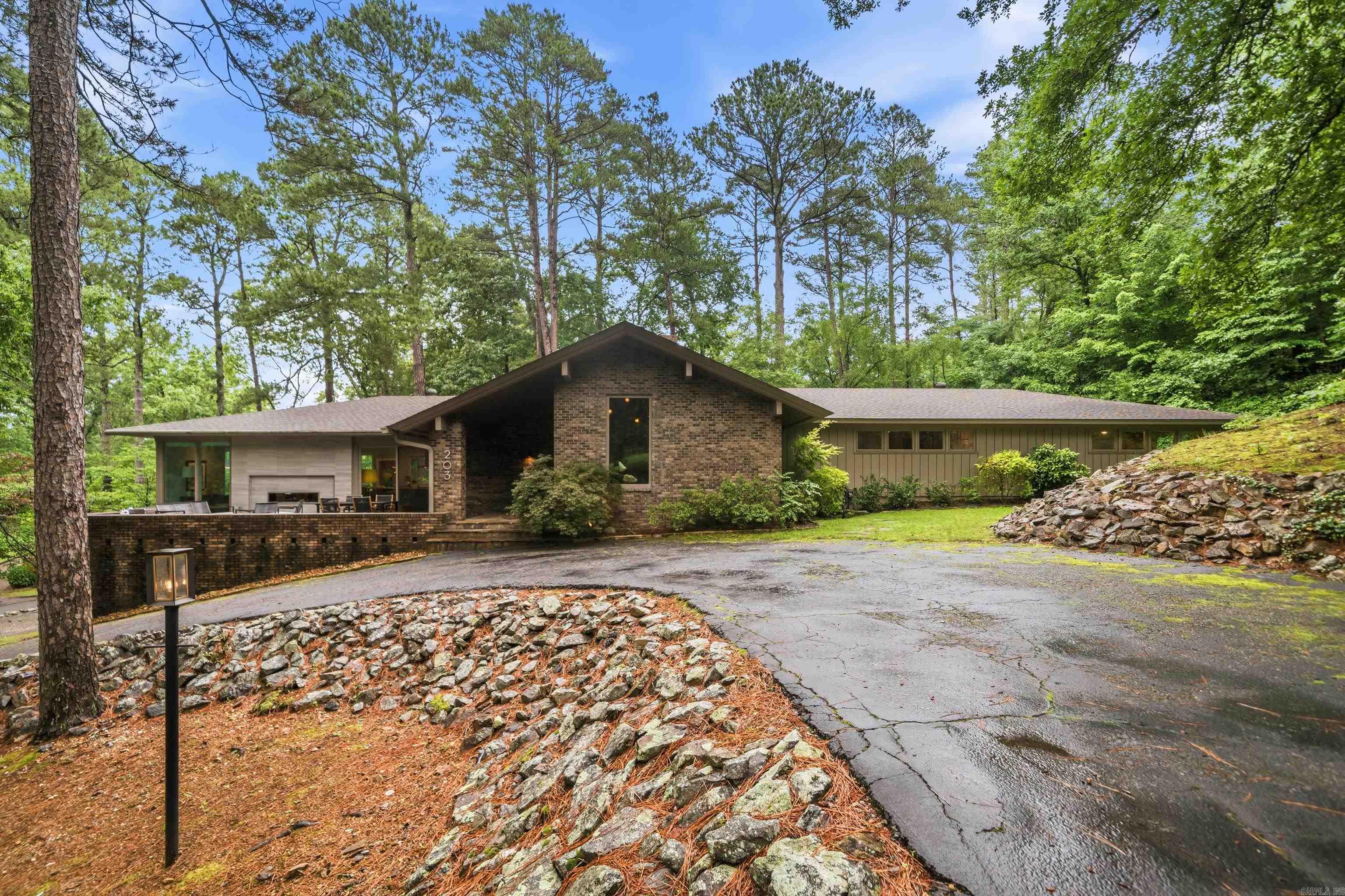 Welcome to this fully furnished mid-century modern dream! Nestled on a beautifully landscaped 1.44-acre wooded lot, it offers ultimate privacy just minutes from downtown and the lakes. Completely remodeled from floor to ceiling, the open floor plan is an entertainer’s paradise. The great room boasts vaulted ceilings, rare corner glass, and a dramatic 16-foot masonry rock fireplace. Full-length sliding doors seamlessly connect the indoors to a brand-new flagstone patio.  This stunning home features 4 bedrooms and 3.5 fully upscale remodeled bathrooms, including a newly added bedroom and en-suite bath. The all-new chef's kitchen highlights custom cabinetry, quartz counters, new appliances, and an expansive wall of windows. Designer-curated updates include all-new electrical, smooth drywall, chic lighting, and a convenient pet bath in the laundry room.  Outside, enjoy professional landscaping, a new sprinkler system, fresh exterior paint, and a newer roof. The finished double garage includes epoxy floors and a built-in workshop. Turnkey and breathtaking, this rare gem is ready for you!