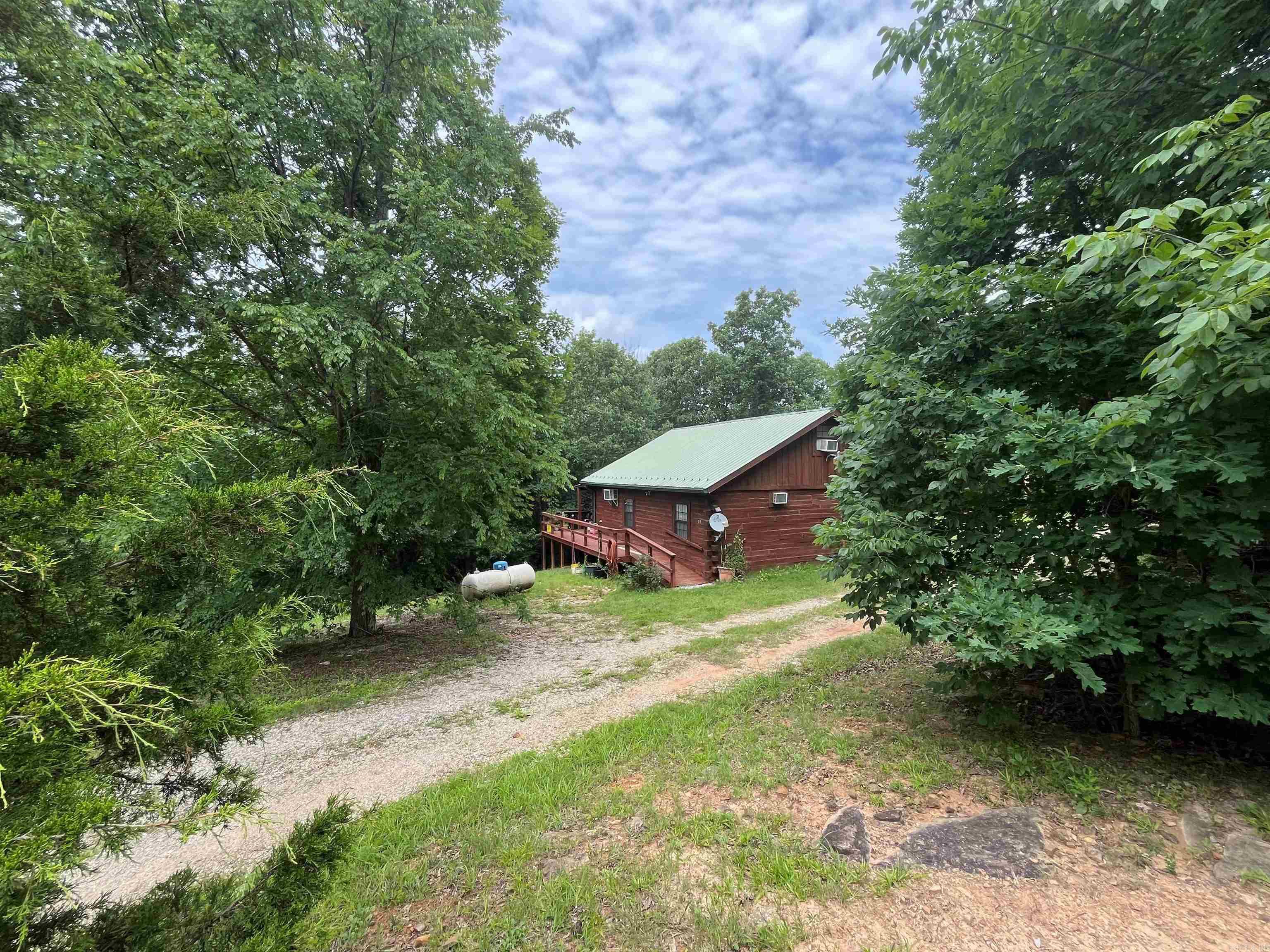 This log cabin sits on 3+/- acres approximately 2 miles from the heart of the Folk Music Capital of the World. It was built in 2010 featuring 960 sq/ft with 2 BR/1 BA. An unfinished loft can add an additional 200+/- sq.ft. of living space. A covered porch is a great place to relax after enjoying the festivities in town. Kitchen appliances and washer and dryer are included. Some furnishings are negotiable. Outside you'll find a 16'x12' storage building with a roll up door and electricity. Beside the building is a 30 amp RV hookup. The 3 acres has a gentle slope and is mostly wooded but open around the cabin. This would make a great starter home or vacation rental.