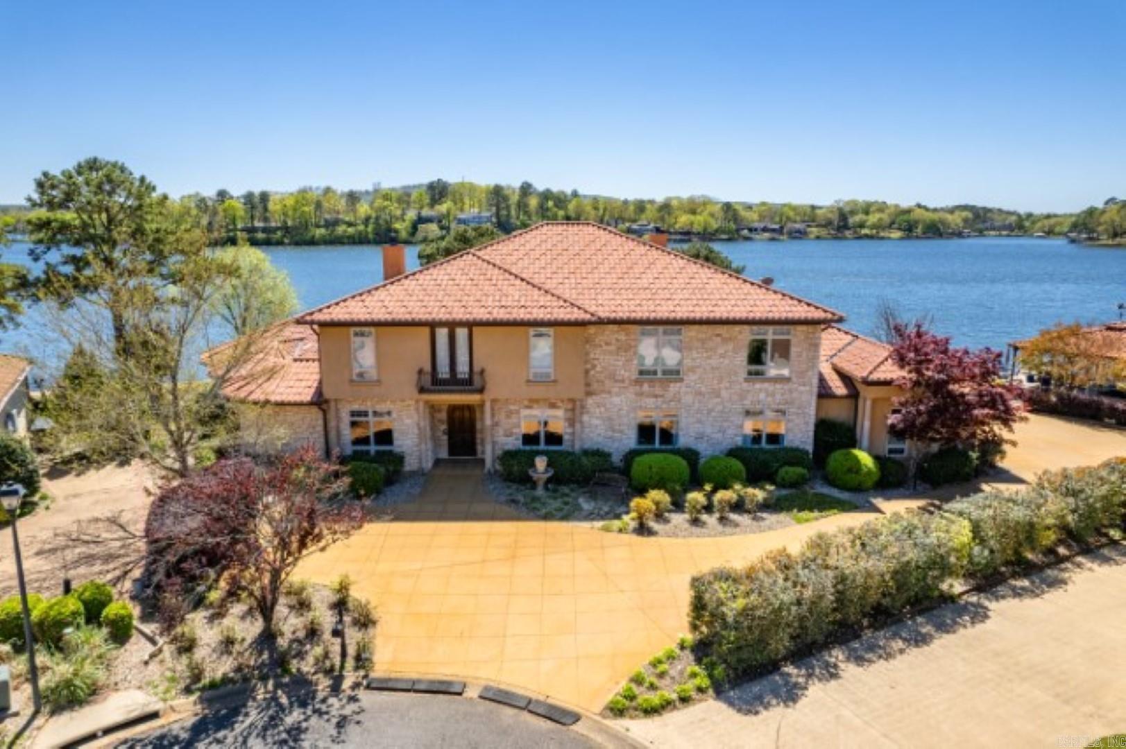 BEST VIEW ON THE LAKE! 5/5/3 lake home. Located on a large level point lot with 260' of lake frontage. Open living concept w/exceptional lake views of the main channel. Beautiful craftsmanship throughout, custom cabinets, granite countertops, crown molding. Hardwood floors in the living room & carpet in all the bedrooms. Sitting room and separate dining room. Upscale kitchen is completely custom and provides every amenity a chef could need. Guests can relax in the hearth room while meals are made. There is a large and private guest bedroom off the exercise/bonus room. Also located on the main floor is an office area/utility room. Each level has a laundry room, for convenience. Master bedroom is luxurious! It features TWO separate master bathrooms, each with its own huge WIC. This bedroom also has a coffee/wet bar and private patio access. This home has its own elevator! On the second floor you will find two guest bedrooms that share a Jack-n-Jill bathroom. A third bedroom with a private bathroom and WIC. Cont'd..