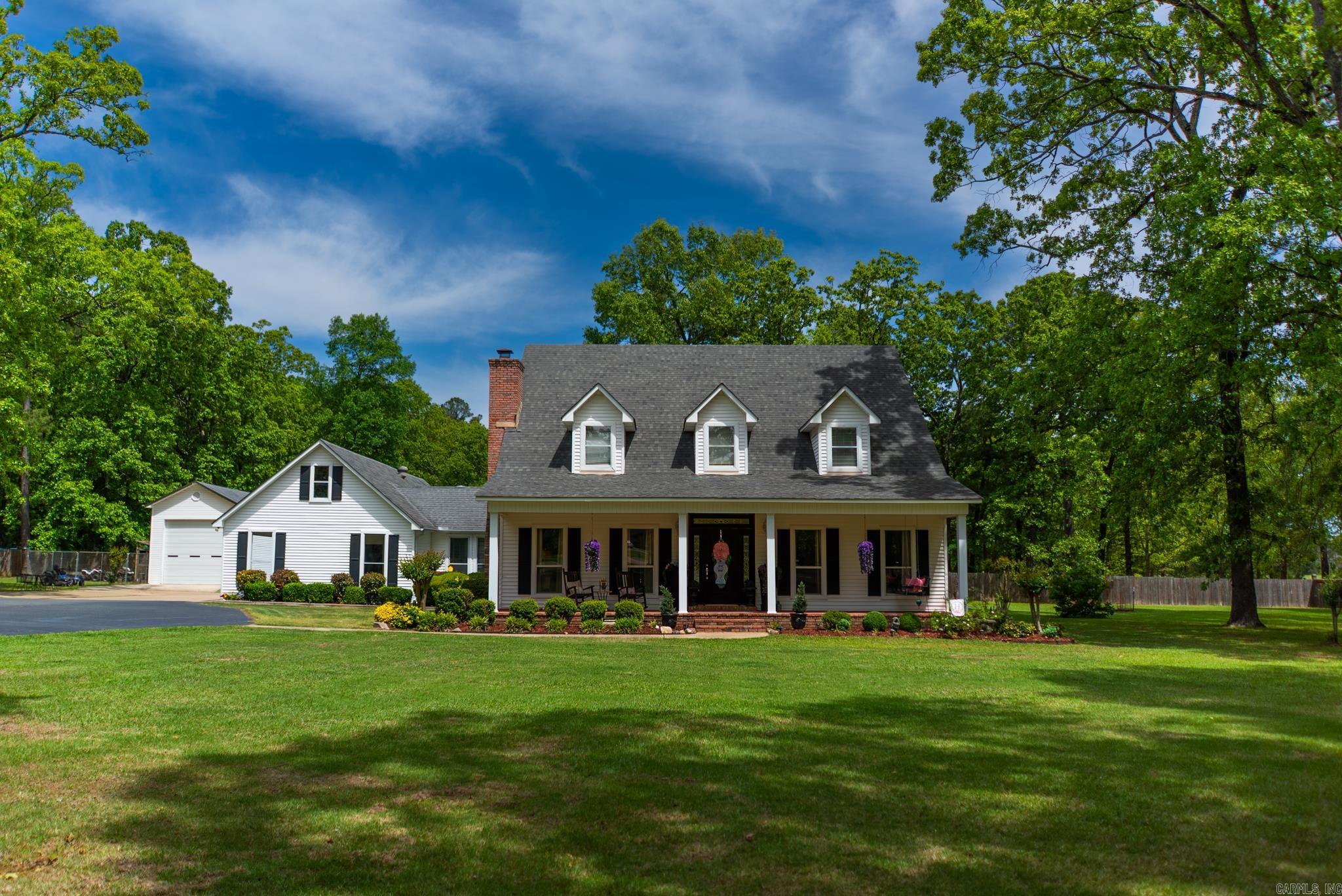 This beautiful white two-story traditional home sits on 2.1 acres inside the city limits, but the real standout is the backyard setup. The spacious patio features a brick fireplace and built-in cooking area, creating the perfect spot for entertaining, watching games, or simply relaxing. The property also includes a large detached boat storage shed, along with a two-car carport and an additional two-car carport with storage in between - offering plenty of covered parking and space for equipment or hobbies.  Inside, the home offers a functional and comfortable layout with four bedrooms. Upstairs features two bedrooms and one full bath. Downstairs includes the primary bedroom, along with a guest bedroom, a full bath, and an additional half bath for guests. The kitchen opens into the den, creating an easy, connected living space, and you’ll also find a laundry room, a breezeway-style mudroom, and a small bonus room that works well as an office or flex space.  If you’ve been looking for space inside and out, with a backyard built for gathering, you’ll want to take a look at this one.