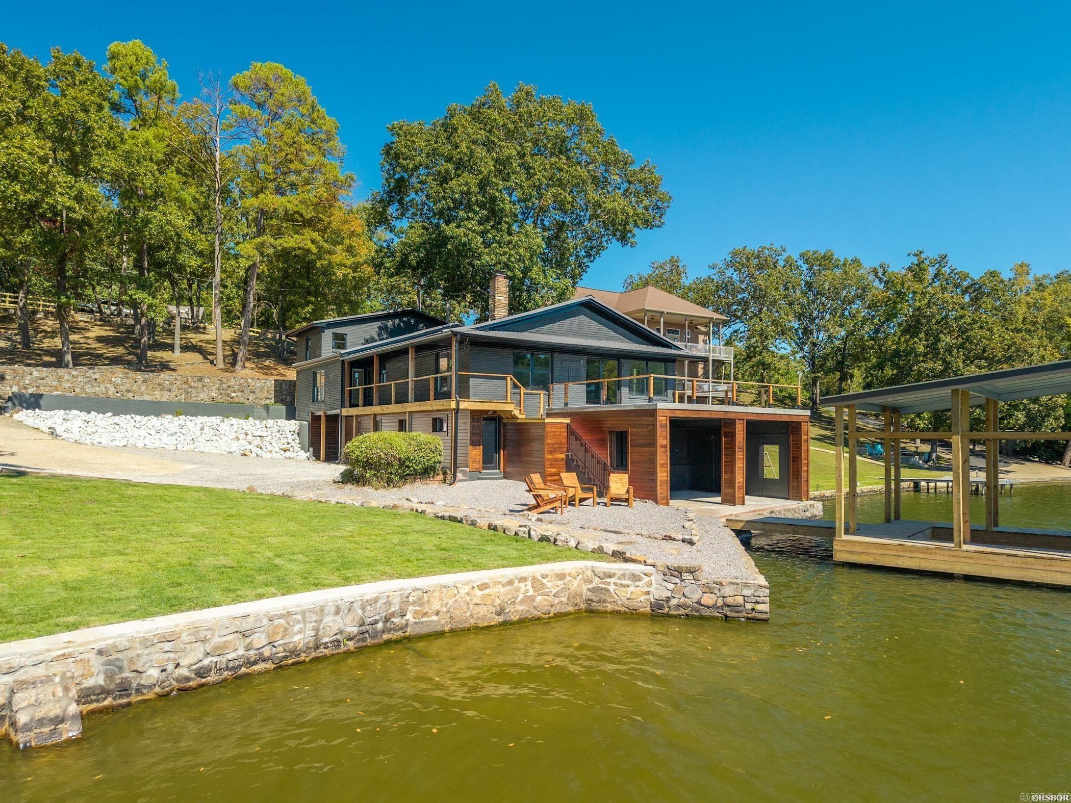 Gorgeous Lake Hamilton home with extra lot! This 6-bedroom, 5½-bath lakefront home has been fully remodeled down to the studs. Every detail of the 4672 sq. ft. home has been updated, incorporating modern finishes with classic lake charm. Updates include all new finishes, electrical, plumbing, fixtures, flooring, and exterior improvements. Situated on just shy of an acre with year-round water views, the home features an open-concept layout filled with natural light. The spacious living areas flow seamlessly into a modern kitchen with premium appliances, quartzite countertops, and stylish cabinetry. Each bedroom comes equipped with a beautifully designed bathroom, and the primary suite is nothing short of spectacular. Each level has its own living area and kitchen. Outside, enjoy a brand-new private boat dock on deep water and two separate patio areas. An additional lakefront lot is included with the home and is permitted for a separate boat slip—ideal for expansion or investment.  Also included is a 1500 sq. ft. workshop/garage structure on the extra lot which would be ideal for another home or guest house to compliment the main home. All brand new furnishings convey with the sale!