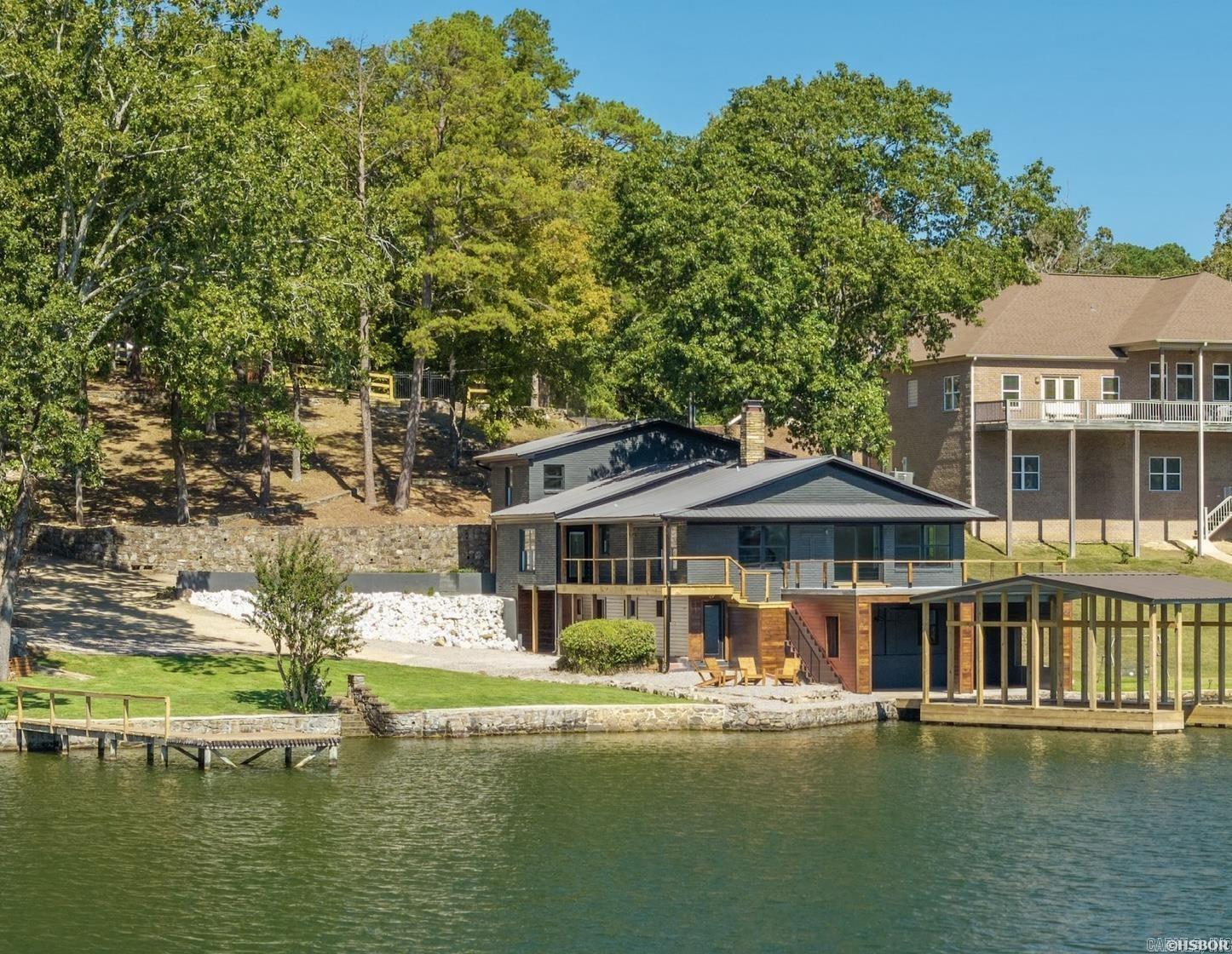 Gorgeous Lake Hamilton home! This stunning 6-bedroom, 5½-bath lakefront home has been fully remodeled down to the studs. Every detail of the 4672 sq. ft. home has been updated with thoughtful design, incorporating modern finishes with classic lake charm. Updates include all new finishes, electrical, plumbing, fixtures, flooring, and exterior improvements. Situated on half an acre with breathtaking year-round water views, the home features an open-concept layout filled with natural light. The spacious living areas flow seamlessly into a modern kitchen with premium appliances, quartzite countertops, and stylish cabinetry. Each bedroom comes equipped with a beautifully designed bathroom, and the primary suite is nothing short of spectacular. Each level has its own living area and kitchen. Outside, enjoy a brand-new private boat dock on deep water and two separate patio areas. All brand new furnishings convey with the sale!  Whether its used as luxury lake residence, family compound or short term rental, this turnkey lake property truly has it all!