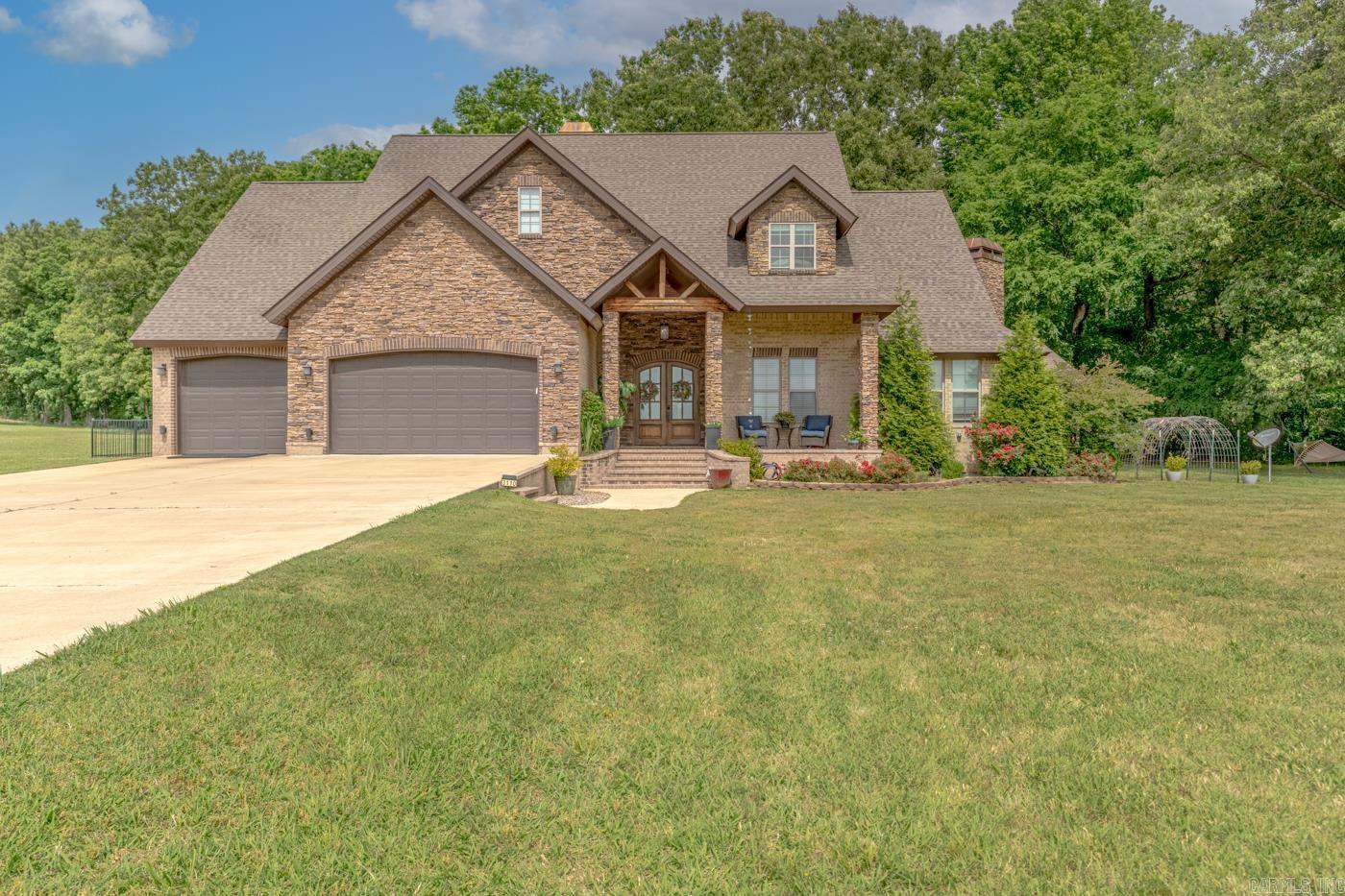 Welcome to Market 3110 Hwy 163 in Jonesboro, AR within the Valley View School District. Situated on 6.36 +/- acres is a 2019 custom built home wrapped in brick & stone and accented by cedar beams, covered front porch & back patio w/ outdoor kitchen and fireplace, 3 car garage, iron fencing, mature landscaping, and forest views. The interior features 3,712 sf of well laid out living space and holds an open concept and split floor plan. From the foyer is the grand living room w/ soaring ceiling w/ wood beams and cozy gas log fireplace. The chef's kitchen holds quartz countertops, island, and stainless steel appliances and the formal dining area boasts a wood burning fireplace. The Master suite offers a vaulted ceiling w/ wood beams and an en-suite w/ walk-in closet, soaker tub, and walk-in shower. 2 spare bedrooms, spare bathroom w/ shower/tub combo, and laundry room complete the main. Upstairs is a 2nd living area, 2 bedrooms, full bath w/ shower/tub combo, and media room. You'll love the chandeliers, custom catwalk, storm shelter in the garage, and floored & insulated attic space. Experience the joys of country living just minutes from town. Call today to make this house your home.