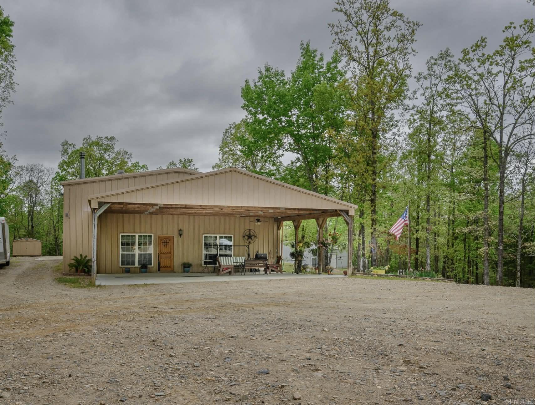Masterfully crafted Barndo with 2 IMPRESSIVE SHOP buildings in the heart of Board Camp!   The open floor plan living space is outfitted with high cedar vaulted ceilings, luxury vinyl flooring, live cedar edge trim and a focal wood fireplace (with blower) that easily warms the entire house!  The beautiful chef’s kitchen includes custom cabinetry, double electric ovens, and gas stove, granite countertops, a 9 ft island and a huge PANTRY!  The primary suite includes a walk-in closet and an accessible bathroom with a custom vanity, double sinks and a dressing table! The second bedroom also has a walk-in closet and both bedrooms are SPACIOUS!   The attached 40x50 shop is ideal for ATV or car lovers. Wired for 220volt It features 2 double garage doors as well as an upstairs with a bonus room and tons of storage space! The 2nd shop sits behind the main house and is 30x50. Additional features include a 35x40 carport, and a covered front “porch”. This is a special property in a prime location!