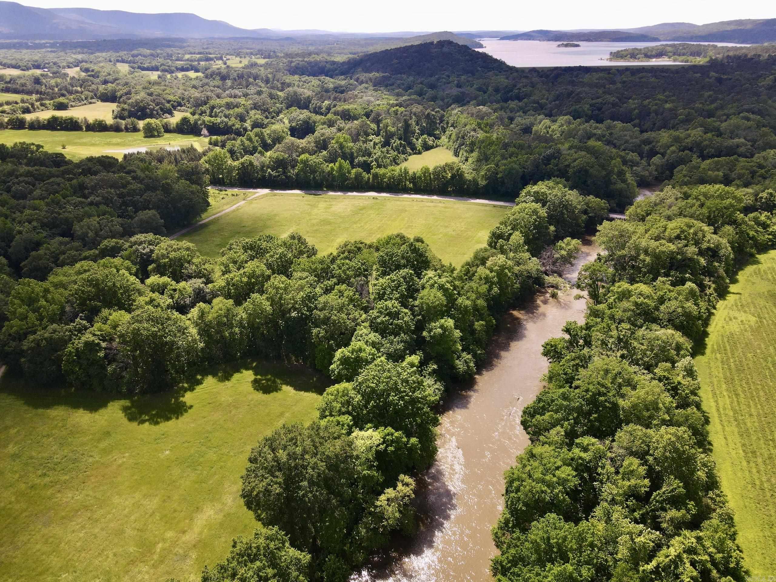 This exceptional multi-use farm with Petit Jean River frontage offers a rare opportunity to own a versatile property with strong agricultural and recreational value. Featuring approximately ¼ mile of Highway 309 frontage with utilities available, the property provides excellent access and a prime building site overlooking the land. A gated entrance and full perimeter fencing add functionality and security.  The Petit Jean River runs through the property for nearly ¾ mile, offering fishing, scenic views, and year-round water access. The land has been used for cattle and is currently producing a strong hay crop, highlighting its agricultural potential. A mix of open pasture and natural areas supports farming, livestock, and recreation.  Bordering the Blue Mountain Recreation Area, the property is minutes from the Blue Mountain Lake boat ramp and near Mount Magazine State Park, as well as the Ozark and Ouachita National Forests.  With abundant wildlife, river frontage, highway access, and utilities, this property is ideal for a farm, recreational retreat, or homesite. Mineral rights do not convey but may be negotiable.