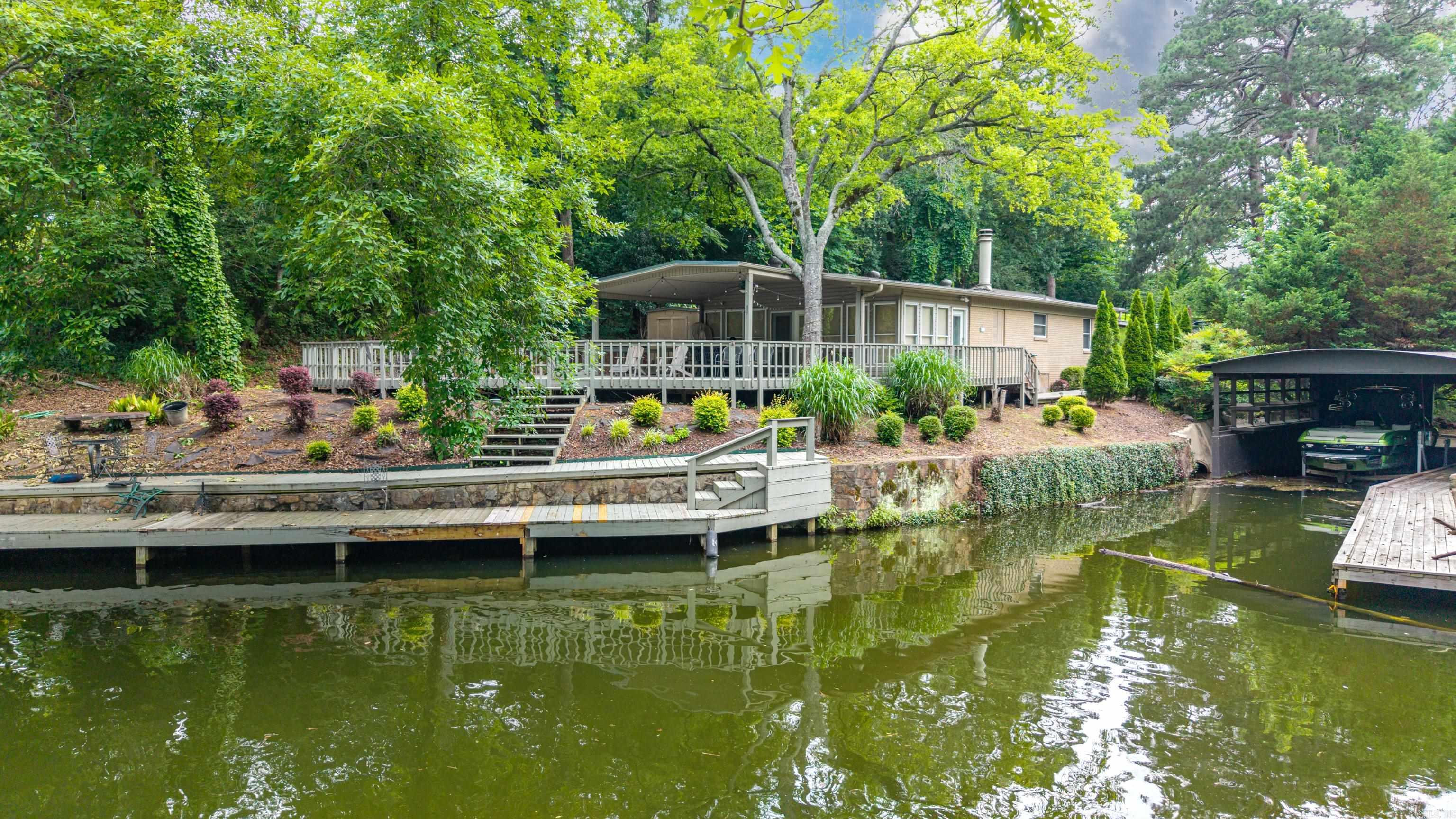 Opportunity awaits with this 3-bedroom, 2-bath home full of character, potential, and investment possibilities.  This property offers great gated  curb appeal and a functional floor plan ready for your updates and personal touches. Whether your looking for a primary resident or investment property, this home presents an excellent opportunity.  Another bonus to this property is the large back deck overlooking the lake, providing a wonderful outdoor space to relax, entertain and enjoy the view. In fact, some of the seller's most treasured memories were made here, sharing time with family and friends. The property features approximately 110 feet of lake frontage with a creek running alongside the property adding to its natural beauty and appeal.  A detached two-car garage provides additional storage and parking convenience.  A VALUABLE BONUS is the existing short-term rental license, providing potential income producing opportunities for investor or those seeking a vacation rental property.  Conveniently located to all the wonderful things to do in Hot Springs Arkansas including Oaklawn Racing Casino Resort, hiking trails, boating, fishing, shopping and dining. Come build your vision