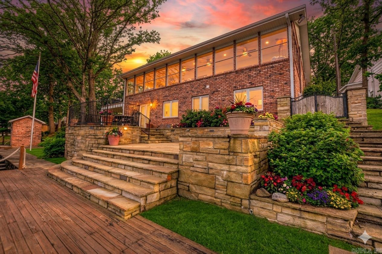 Situated on 95' of Lake Hamilton shoreline, this 4,200 SF brick estate offers a masterclass in lakeside luxury. Extensively renovated in 2023, the open-concept main level features hardwood floors and a gourmet kitchen with marble counters, a gas cooktop, and a wet bar with a brass sink. Walls of glass open to a full-length sun room with panoramic views and deck access. The main-floor primary suite includes a walk-in closet and a bath with a stackable W/D. The lower level offers four bedrooms, two baths, and a large laundry room, with French doors leading to a stone patio. Two additional bedrooms and a bath reside on the upper level.  Exquisite craftsmanship is found in every detail. The exterior is a waterfront paradise: a shoreline boardwalk, an oversized detached garage, and a premier boat dock (updated 2026) featuring two remote-controlled hydraulic lifts, two PWC slips, and a swim deck. Recent upgrades include a new roof and front windows (2023) and a new hot water tank (2026). Located in a quiet luxury enclave with no HOA, this home perfectly balances sophisticated design with lakefront utility.