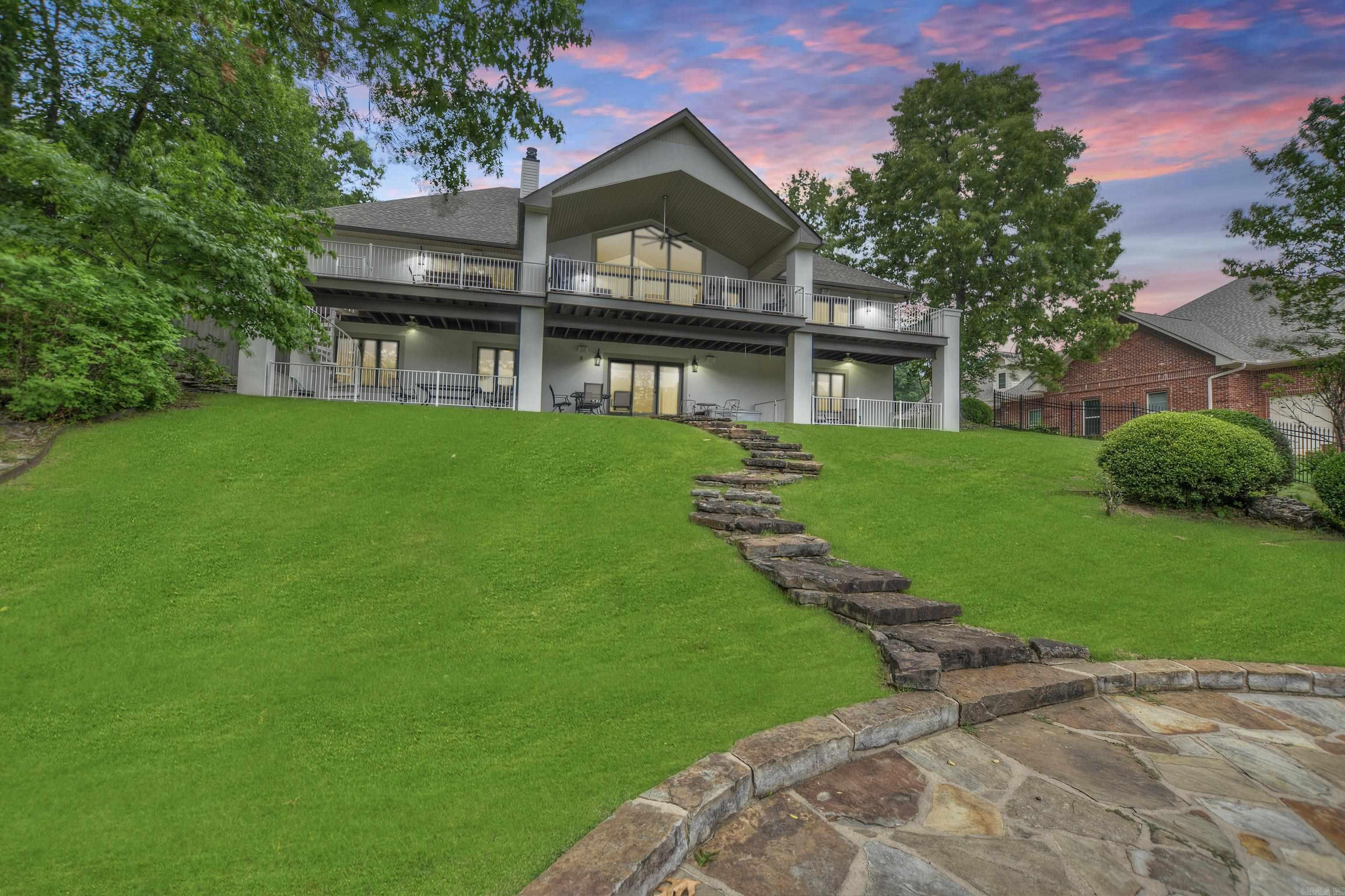 Modern 4,560 SF lakefront home with panoramic views in one of Hot Springs' most desirable neighborhoods. Features include triple-car garage, chef’s kitchen with black granite & high-end stainless appliances, double-sided gas fireplace, and main-level primary suite. Walls of glass open to expansive deck; lower level offers 3 guest rooms, 2 baths, 2nd living area, kitchenette, wine storage, and walkout to covered patio & fenced dog run.  Recent upgrades: new roof, gutters, exterior paint, carpet, and fencing (2024-2025). Includes 2-stall covered boat dock with hydraulic lift & PWC pad. Gated community with pool, clubhouse, tennis/basketball courts, boat ramp, and RV storage. No short-term rentals. HOA $700/yr.