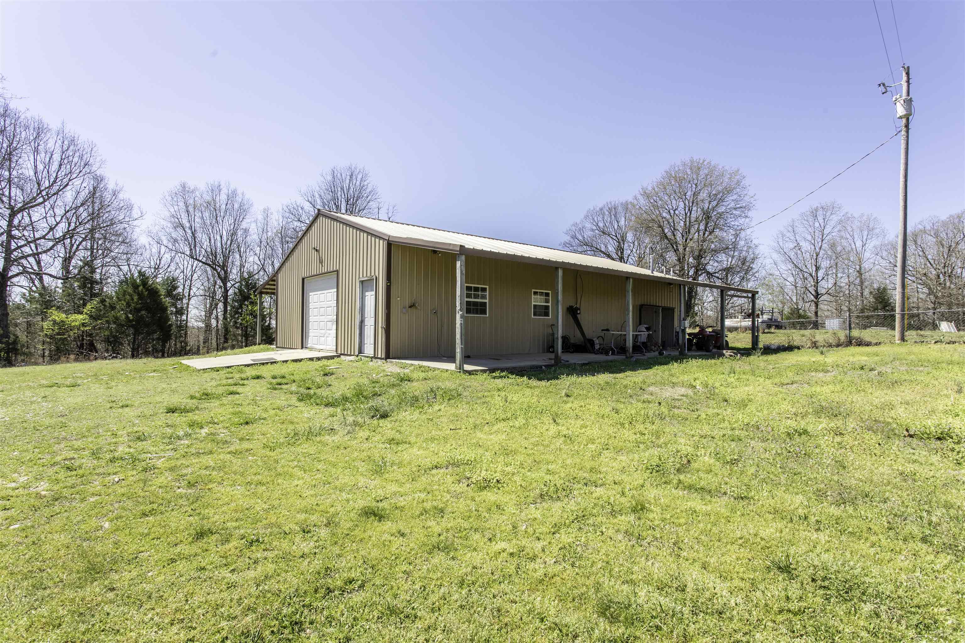 **Shop House / Barndominium on 7 Acres – No Restrictions**  Looking for a property with room to grow? This versatile **1,500± sq. ft. shop house/barndominium** offers endless possibilities on **7 unrestricted acres** with a mix of open lawn and wooded acreage.  Approximately half of the building has been finished into a comfortable living space featuring a **bedroom and bathroom**, while the remaining area is ready for your vision. The entire structure is serviced by **central heat and air**, and all interior walls have already been finished with drywall, making it easy to complete additional living space such as a full kitchen, living room, and extra bedrooms if desired.  Outside, you'll find a **portable storage building** and **covered storage area** for equipment, vehicles, or recreational gear. The land offers a nice balance of open ground and timber, providing privacy, room for animals, gardening, recreation, or a future hobby farm.  With **no restrictions**, this property is ideal for a variety of uses including a residence, workshop, home-based business, hobby farm, or weekend getaway.   Adjoining properties may also be purchased to expand your investment.