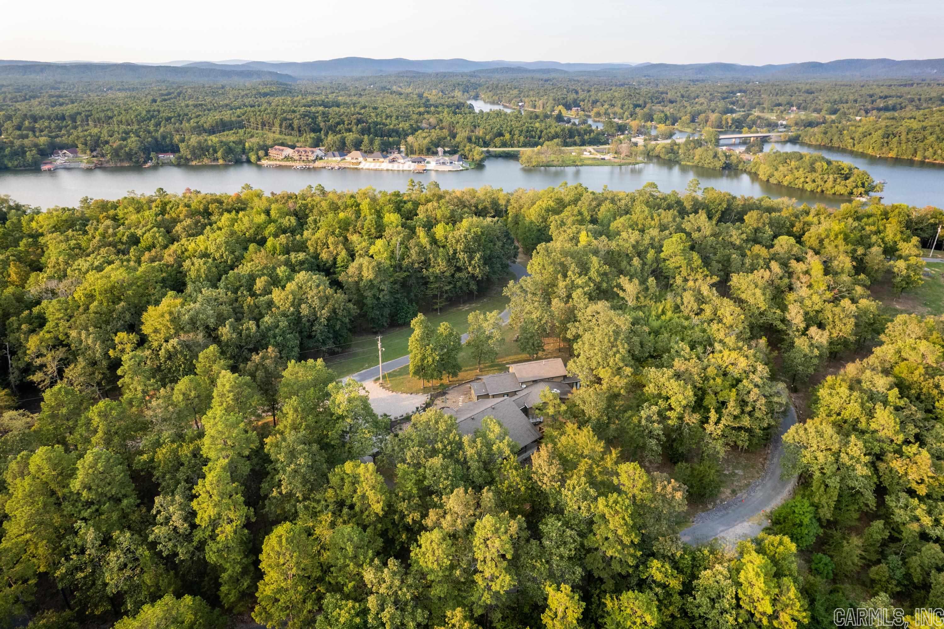 This gated Lake Hamilton Estate boasts over 1,000 feet of shoreline and 19+ secluded acres.  This hidden gem is nestled amidst timber, providing a haven for abundant wildlife and daily deer sightings. At the heart of this estate stands a 5000+ sq ft home, positioned perfectly to soak up the expansive vista/lake views. Currently an established income-producing nightly rental, this property offers endless potential & will pay for itself.  The main house was thoughtfully crafted with exquisite indoor/outdoor amenities, including an impressive underground wine cellar with a private patio door, perfect for enjoying the sunsets. Culinary enthusiasts will fall in love with the chef’s kitchen, & the home features two main-level primary suites, with plenty of room to entertain friends & loved ones. In addition to the stunning residence, this property presents endless opportunities for various endeavors. The detached shop with additional barndominium-style apartment / full bathroom offers extra space for guests, & convenient boat storage.  With city water & two electric meters already in place, this property is an ideal retreat for both personal enjoyment and potential investment purposes.