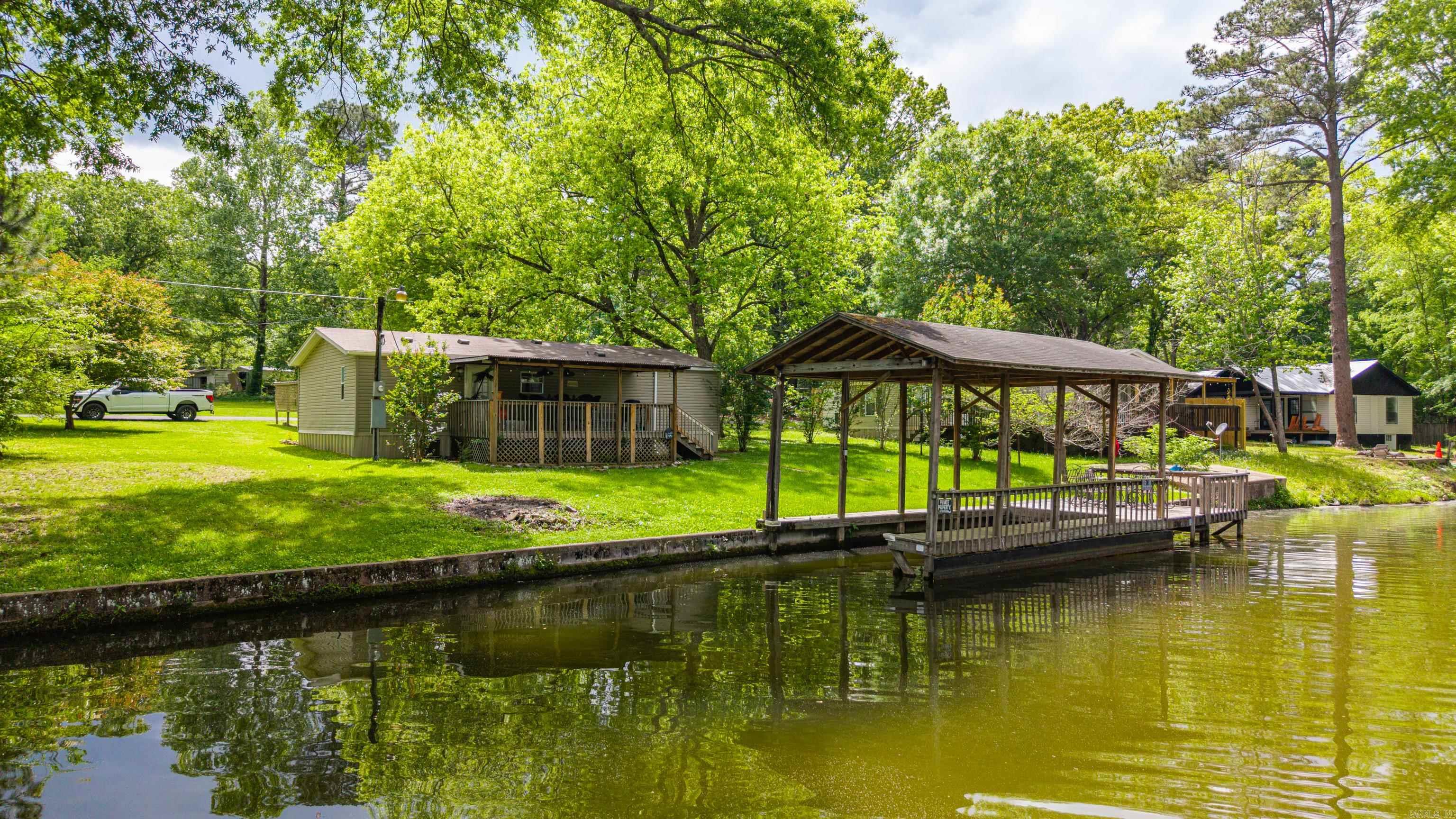 Welcome to your perfect lake escape! This beautifully maintained 3 bedroom, 2 bath home is full of warmth, charm, and endless possibilities for making memories on the water. Nestled on a rare flat, level lot, you can step outside and enjoy effortless access to the lake, whether it’s for morning coffee by the shore, afternoons in the sun, or evenings watching the water sparkle.  The covered boat dock is ready for days of boating, fishing, and fun, while the carport adds convenience. Inside, the home has been lovingly cared for and offers a comfortable, move-in ready space to relax after a day on the lake.  Located in a prime spot with a great location on the lake, this inviting property is perfect as a full-time home, vacation retreat, or weekend getaway. Come experience the easy, peaceful lifestyle of lakefront living!